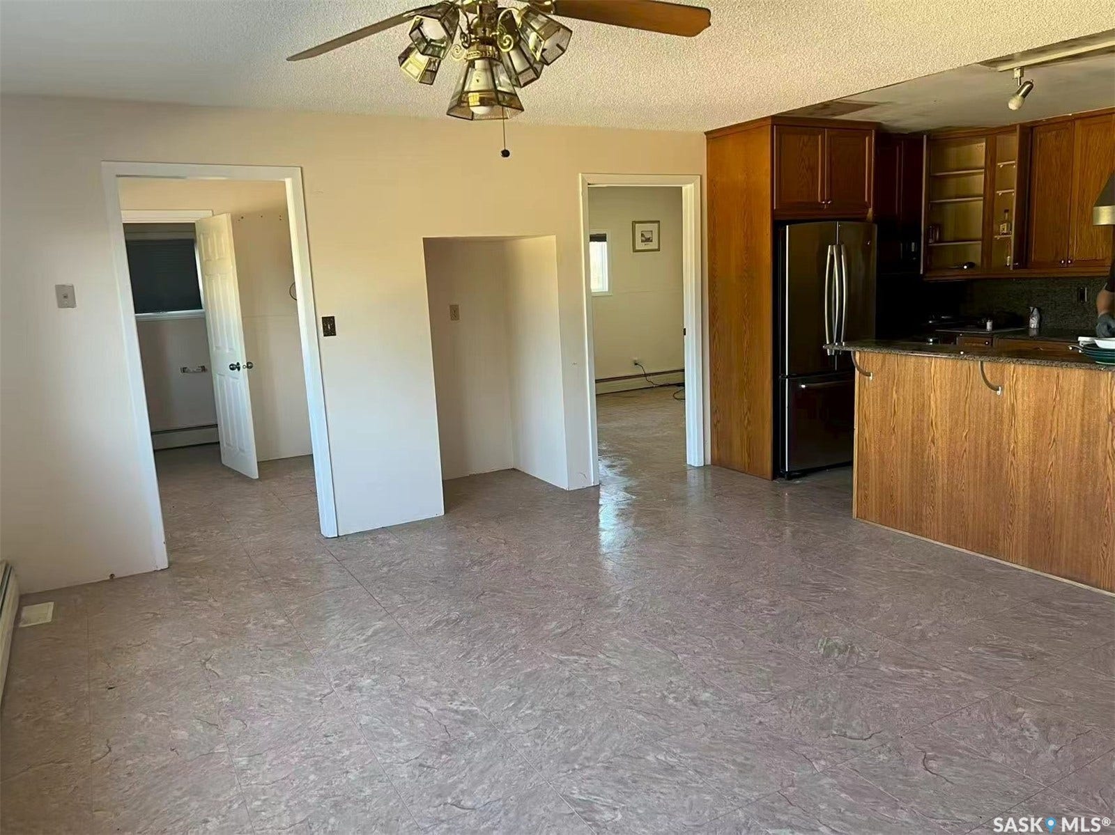 Kitchen area with wood cabinetry, dark countertops, and stainless steel refrigerator
