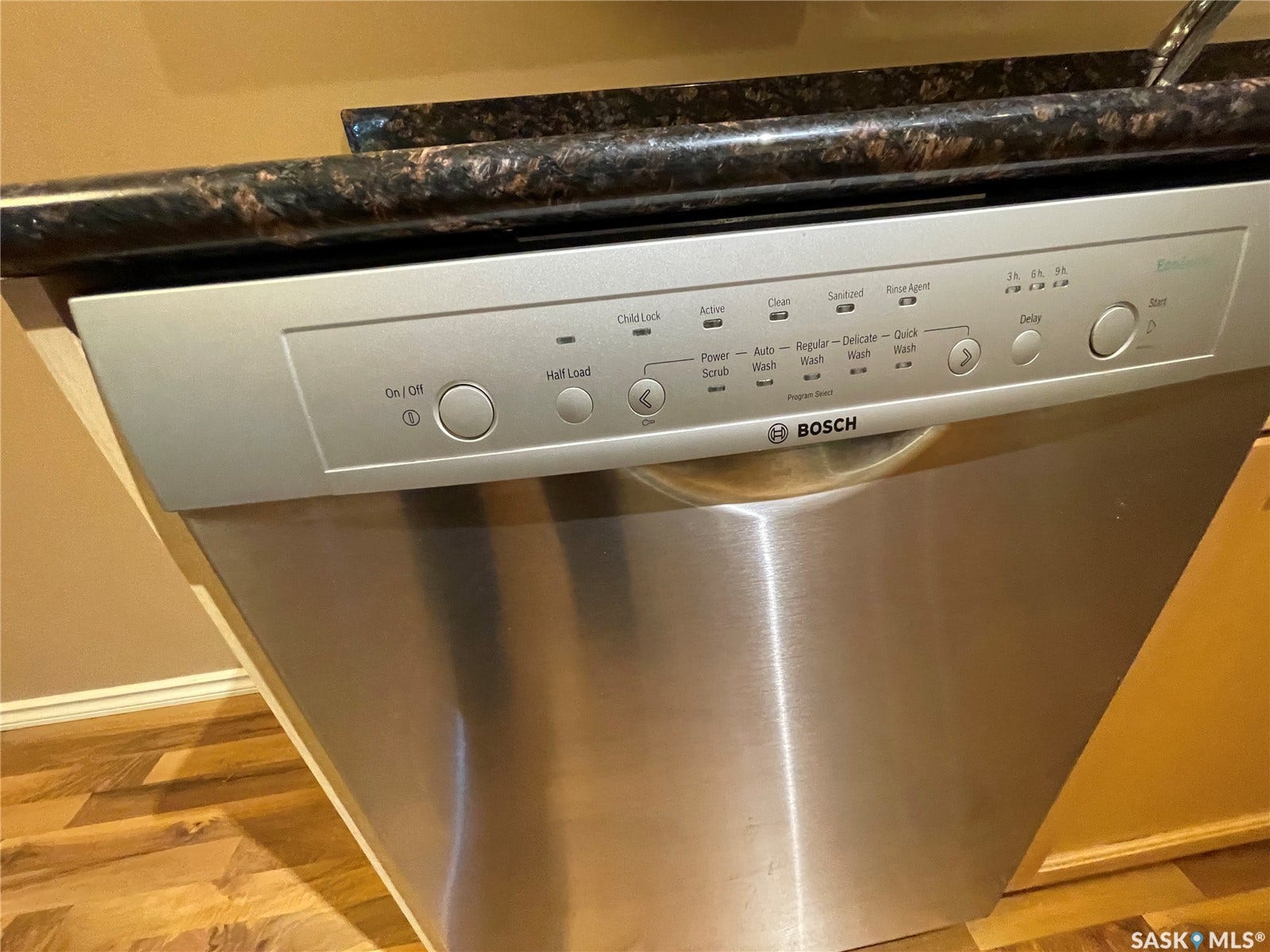 Stainless steel Bosch dishwasher with a dark speckled countertop, light wood-finish flooring, and light wood cabinetry