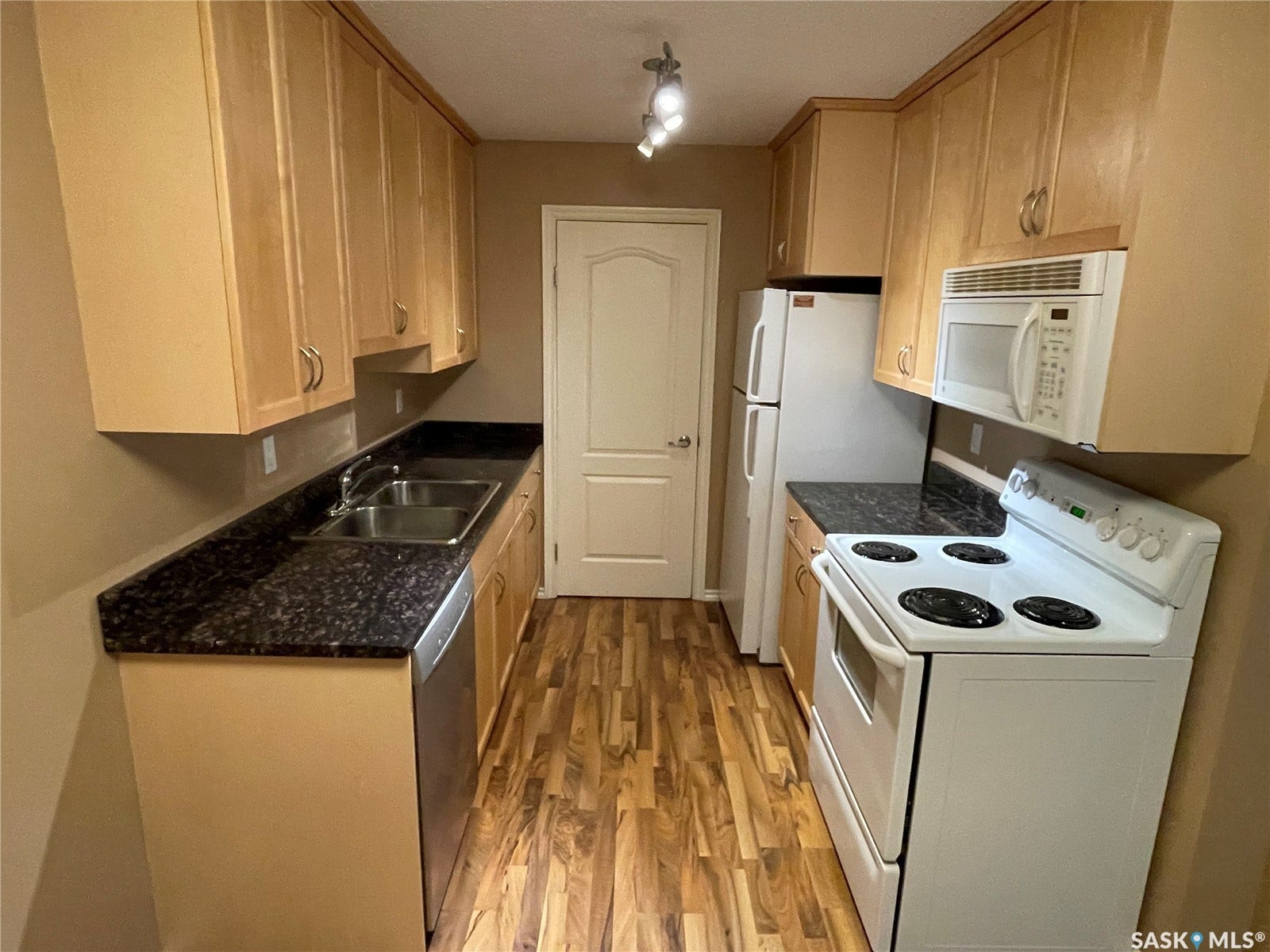 Kitchen featuring wood-finish flooring, full-height cabinetry, dark speckled countertops, and a double basin stainless steel sink