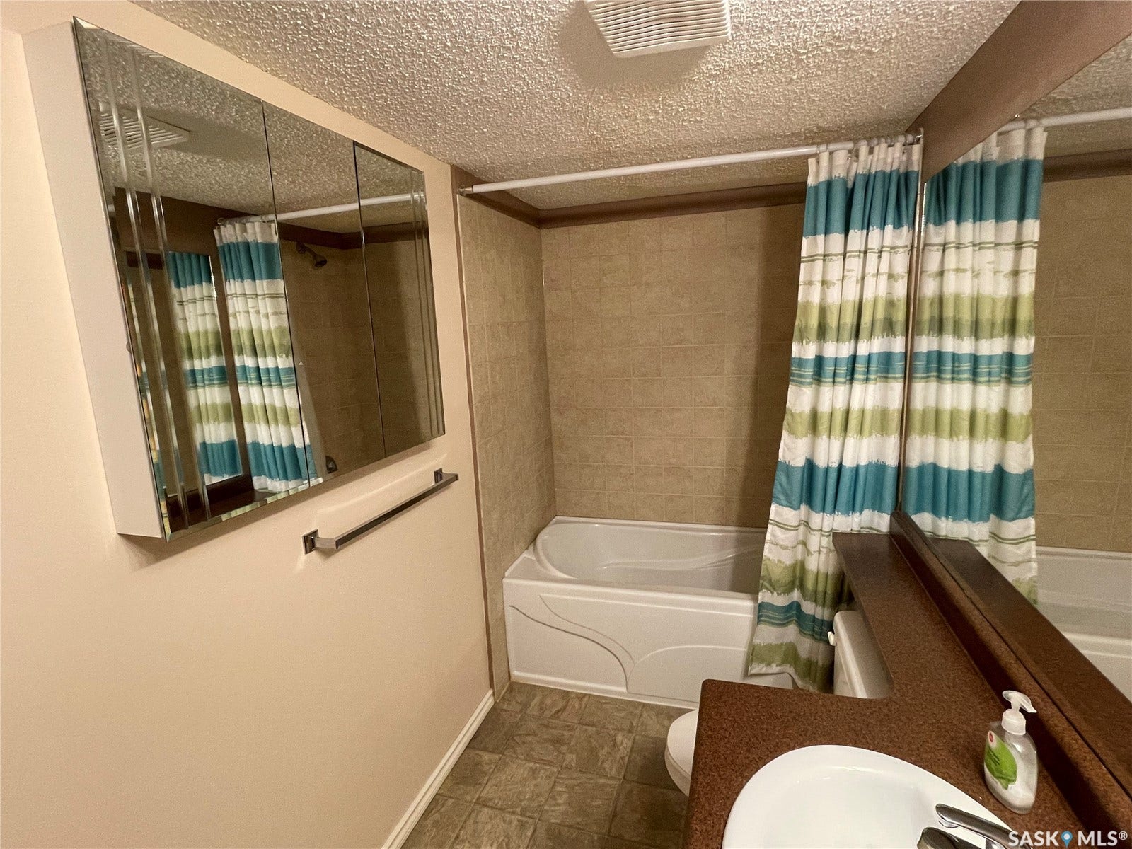 Bathroom featuring a white bathtub, vanity with integrated sink, and wall-mounted mirrored medicine cabinet