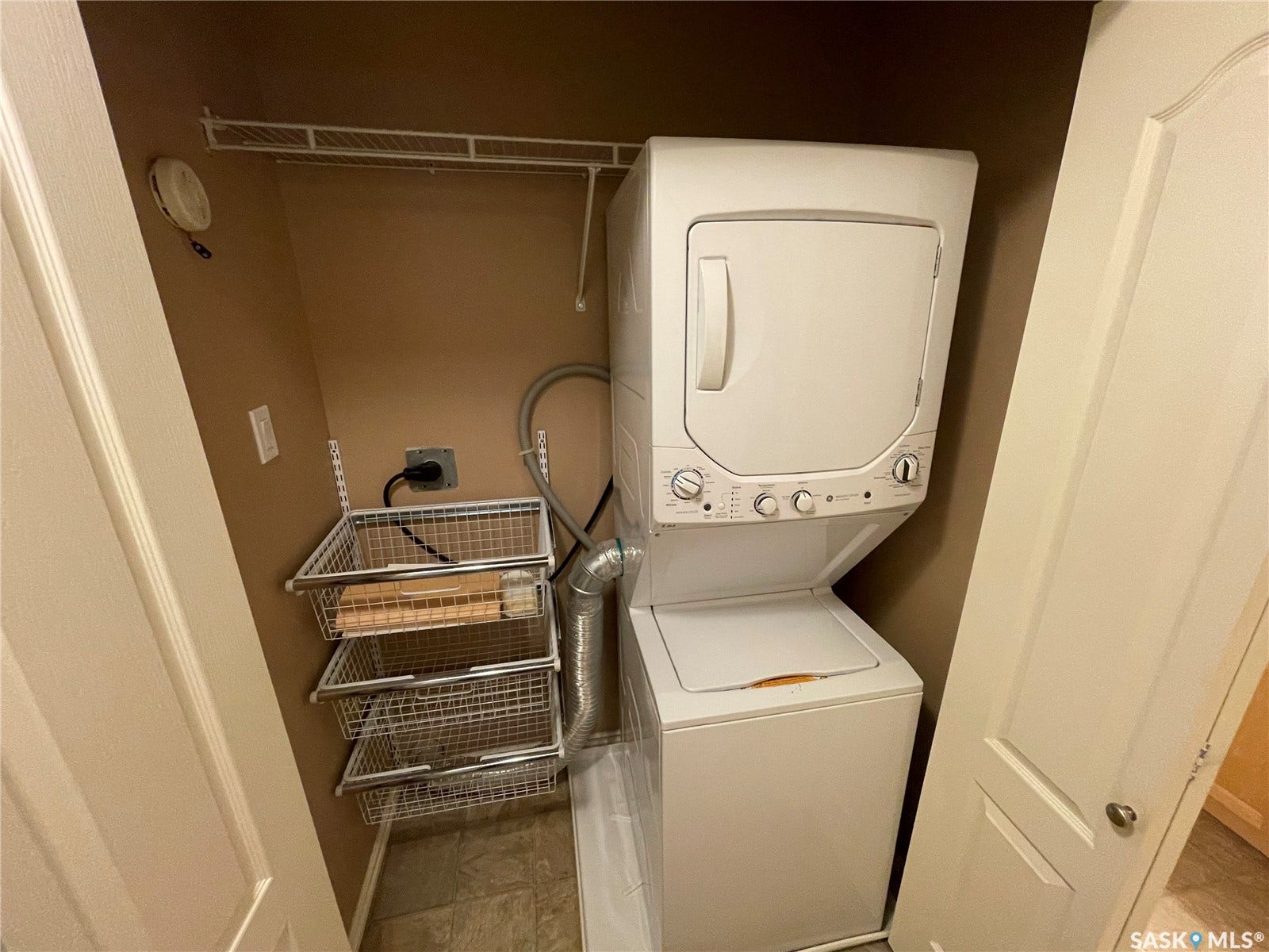 Laundry closet featuring a stacked white washer and dryer, wire shelving.