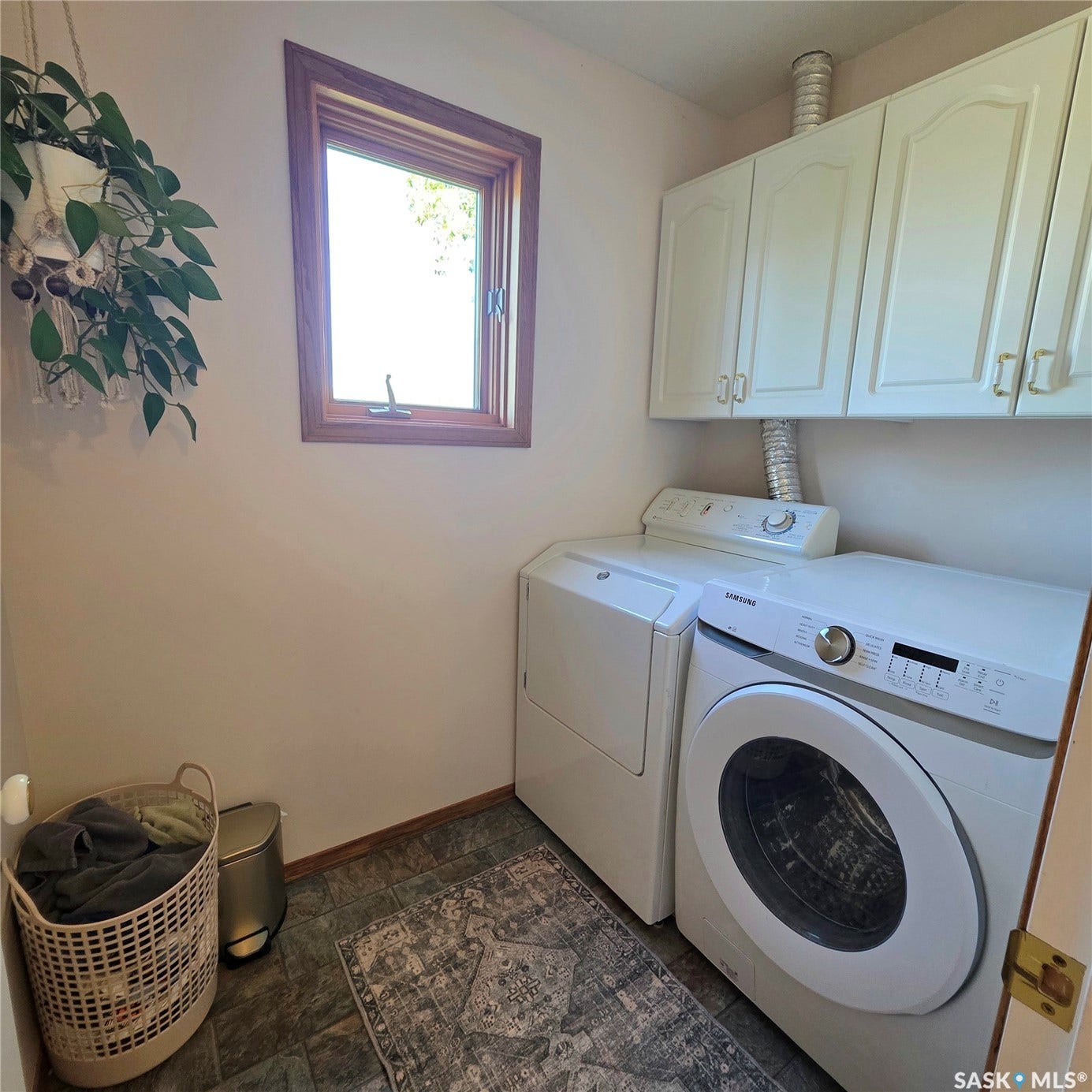 Window with wood-finish trim, upper cabinetry, and tile flooring