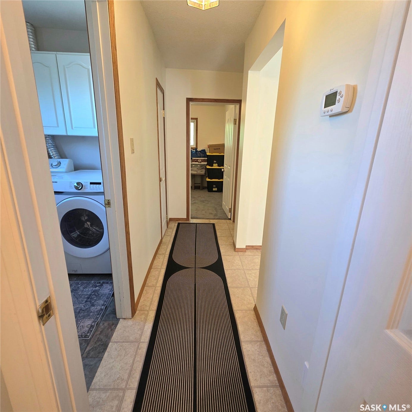 Hallway with tile flooring, white walls, and wood-finish trim