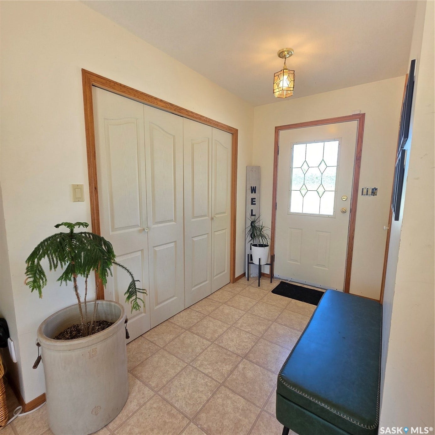 Entryway featuring light-toned square tile flooring, a white paneled door with decorative glass inserts, and a flush-mount ceiling light fixture with a geometric design