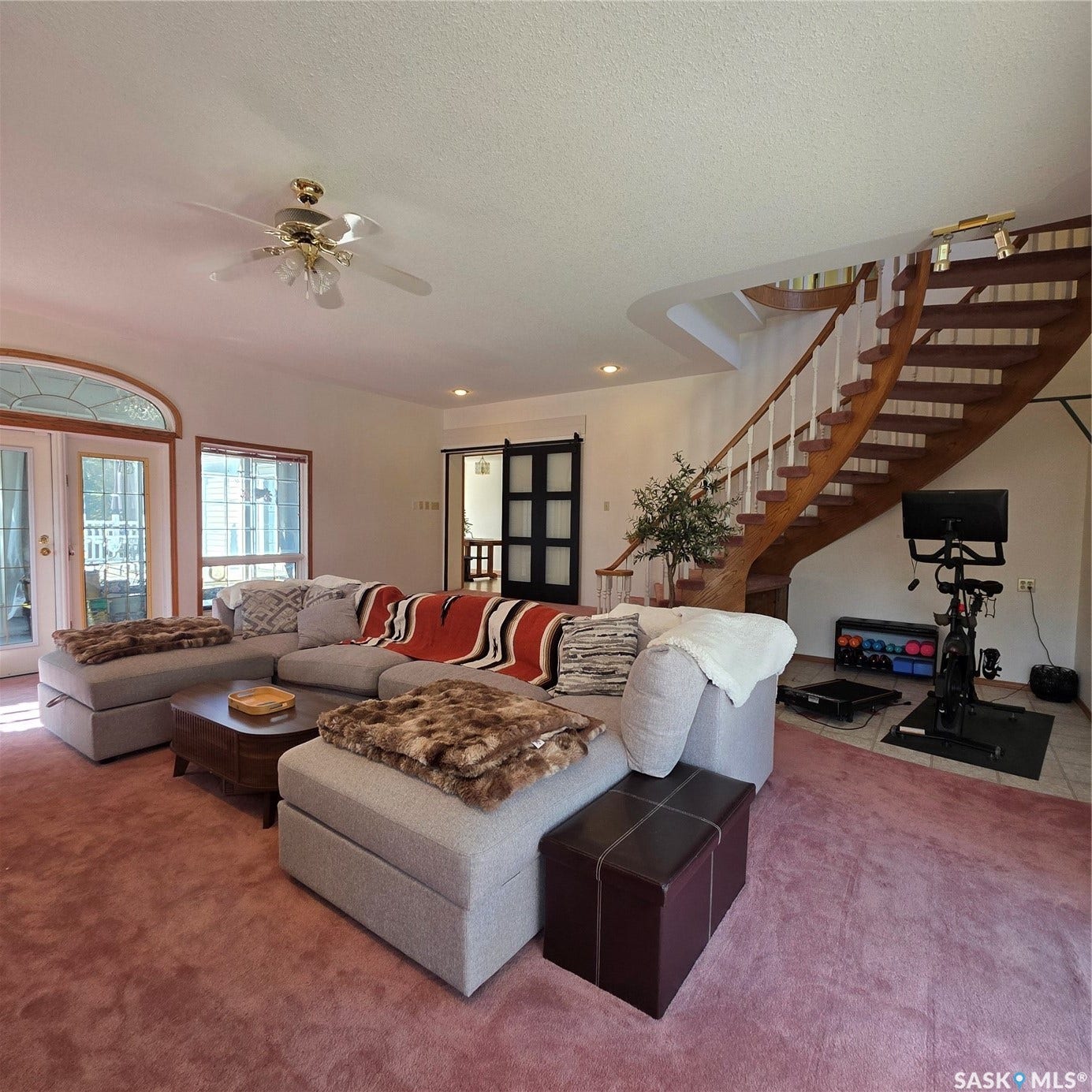 Arched transom window, double French doors, recessed lighting, ceiling fan, and curved wooden staircase with white balusters