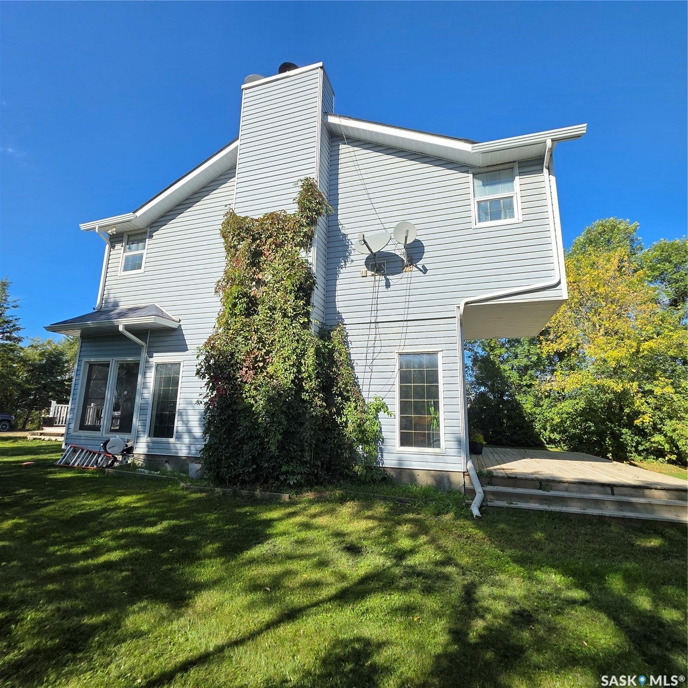 Light blue horizontal siding, multi-pane windows, and an exterior chimney