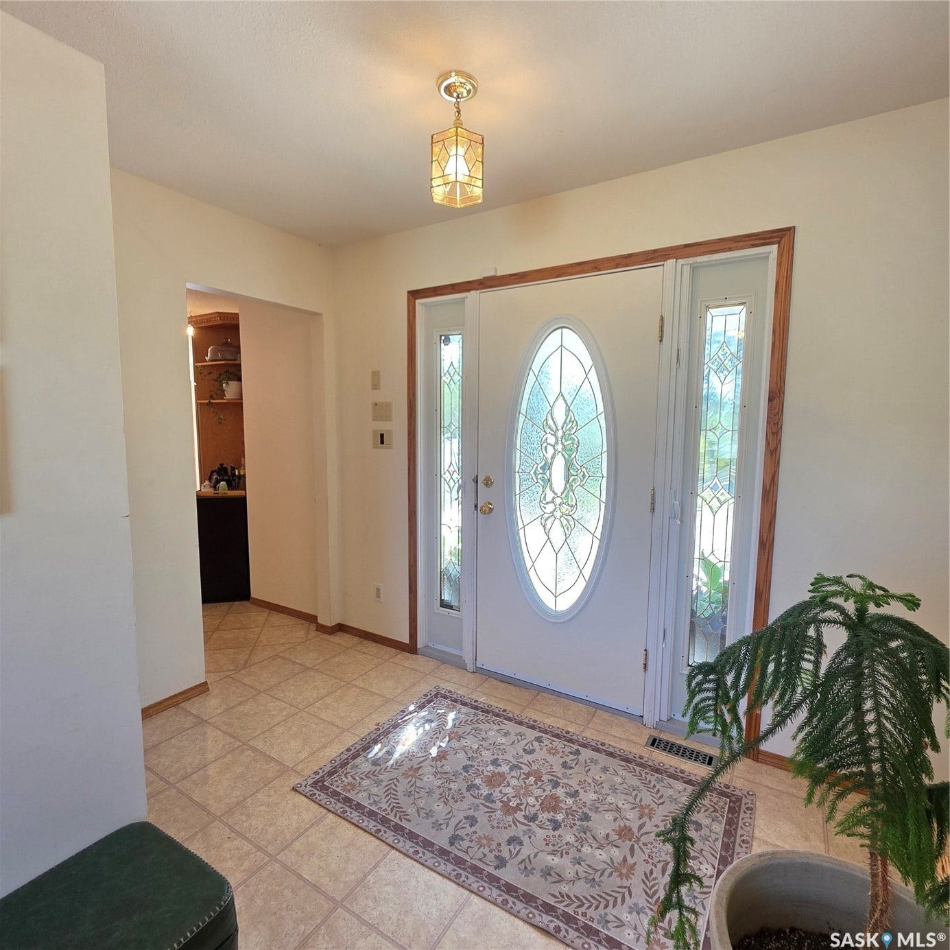 Entryway featuring a decorative oval-inset front door, two sidelight windows, a tiled floor, and a polished brass ceiling light fixture