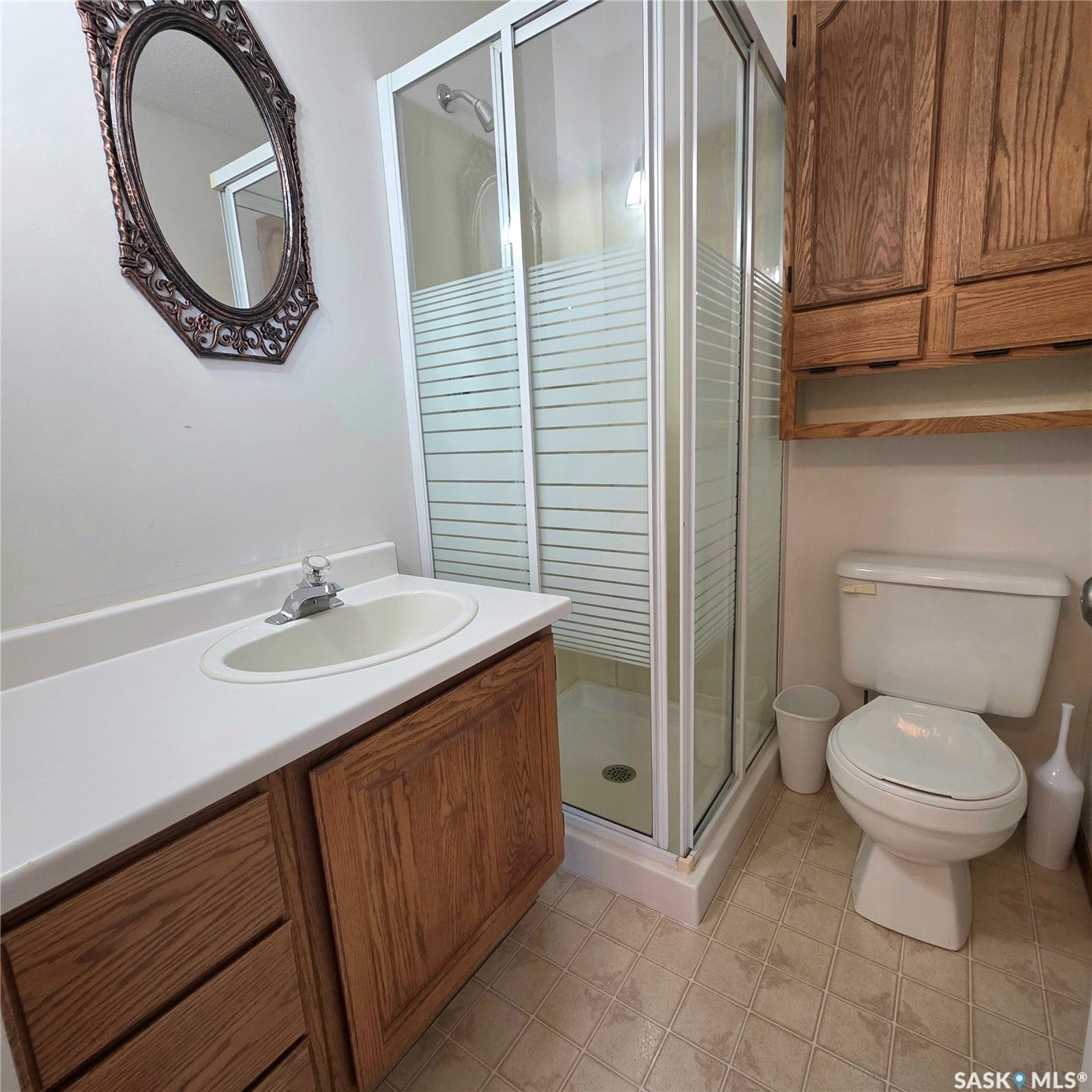 Full bathroom featuring a single vanity, wood-finish cabinetry, and a glass-enclosed shower with frosted detailing