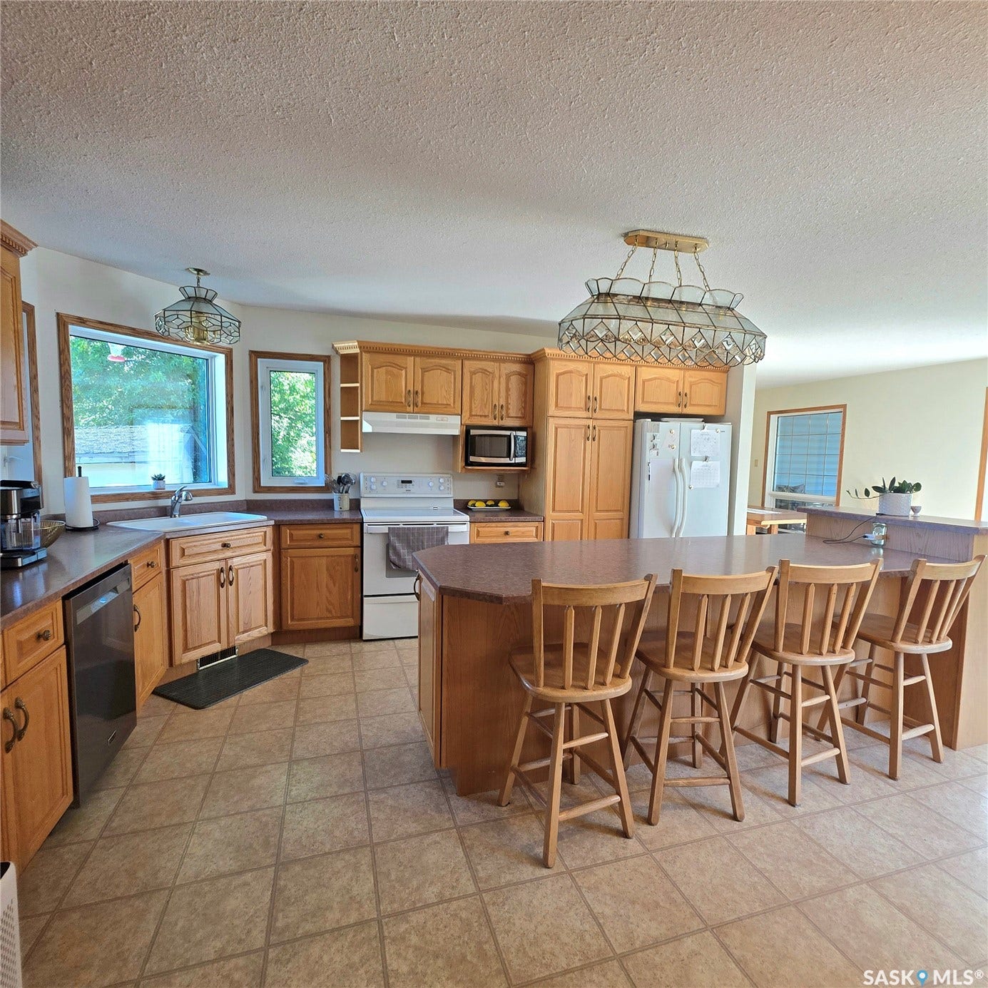 Kitchen featuring wood cabinetry, an integrated kitchen island with seating, a built-in double basin sink, and tile flooring