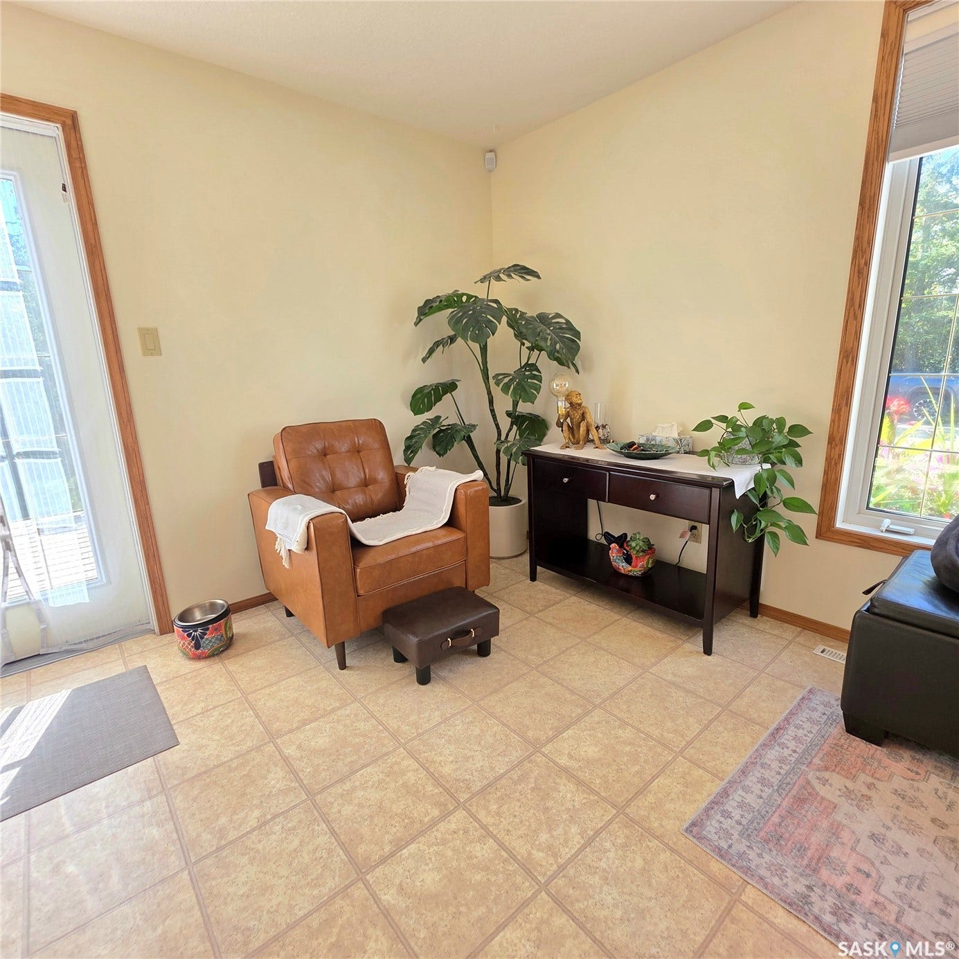 Tiled flooring with a warm finish, complemented by a large window and a glass-paneled door
