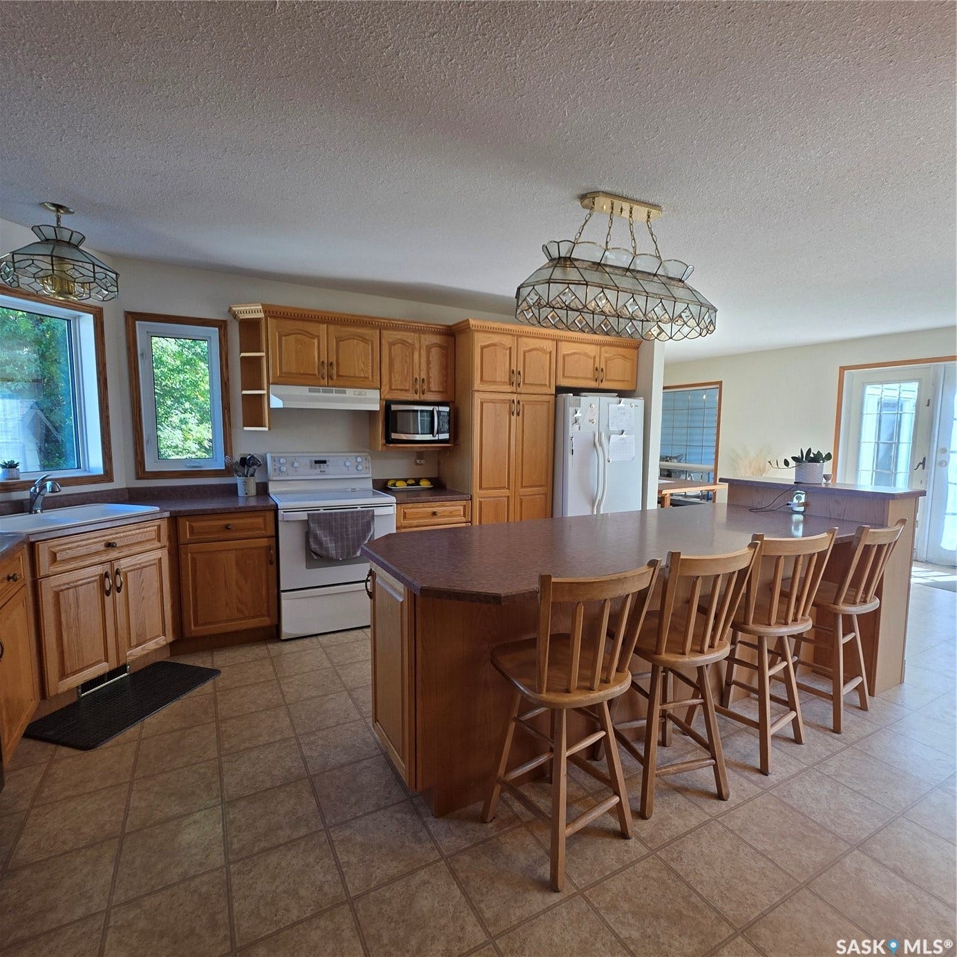 Kitchen featuring an eat-at island, light wood-finish cabinetry, tile flooring, and multiple windows