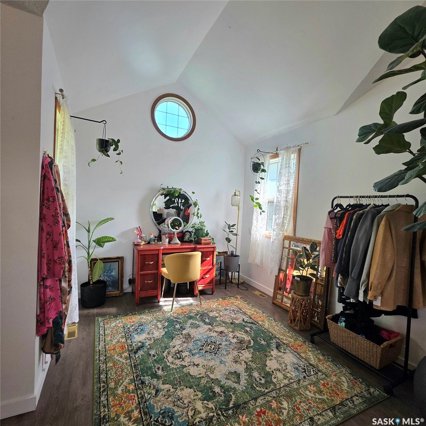 Vaulted ceiling with a round transom window, wood-finish flooring, and a large window with natural light