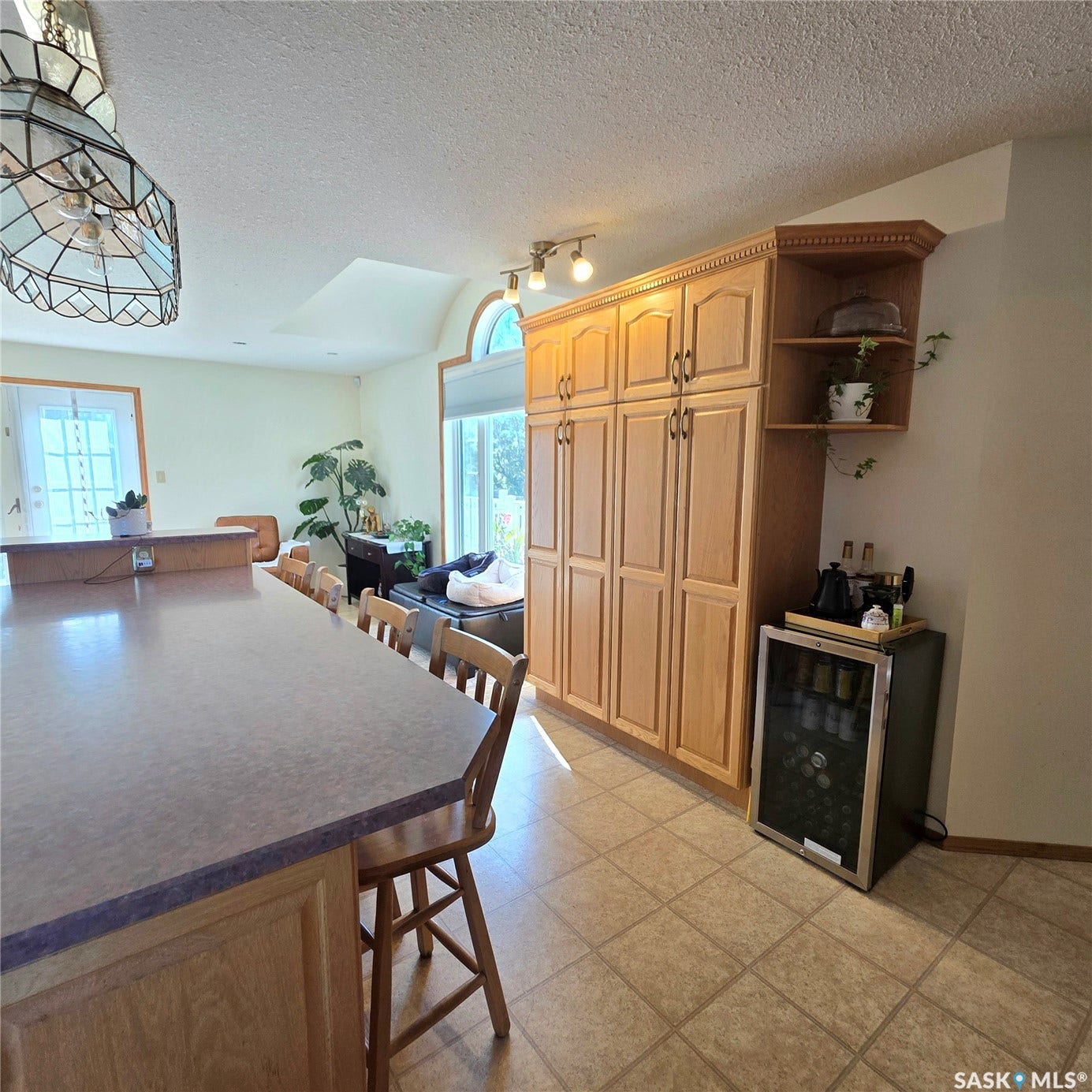 Kitchen island with seating, ample wood cabinetry, tile flooring, built-in shelving, and a beverage refrigerator
