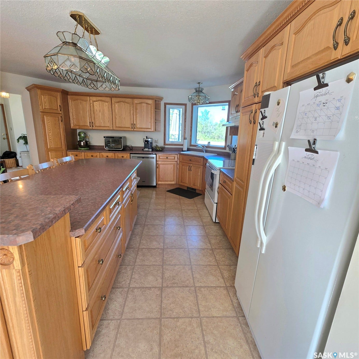 Kitchen featuring light wood cabinetry, a large center island with an extended countertop, and tile flooring
