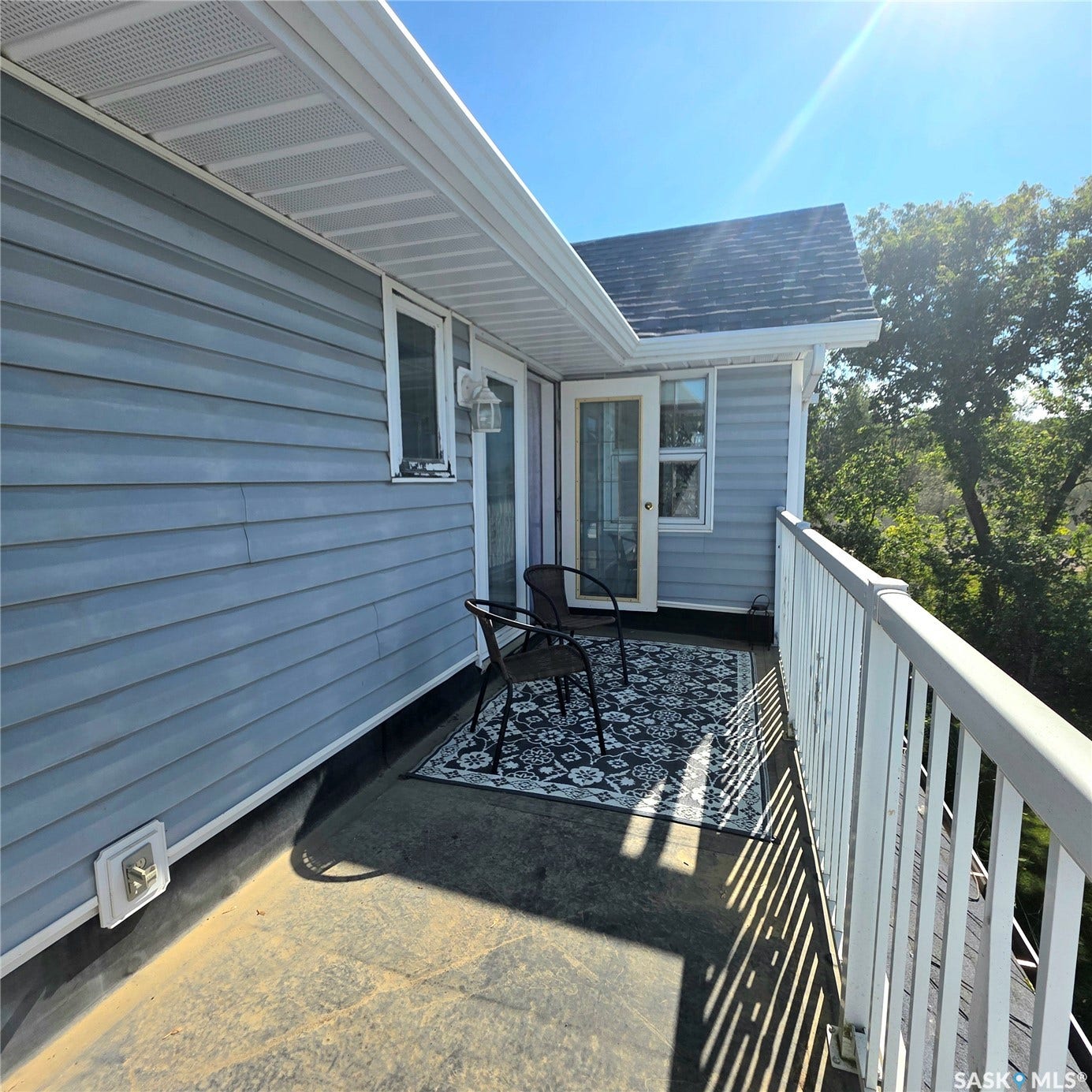 Private balcony with exterior siding, white railing, and an outdoor light fixture