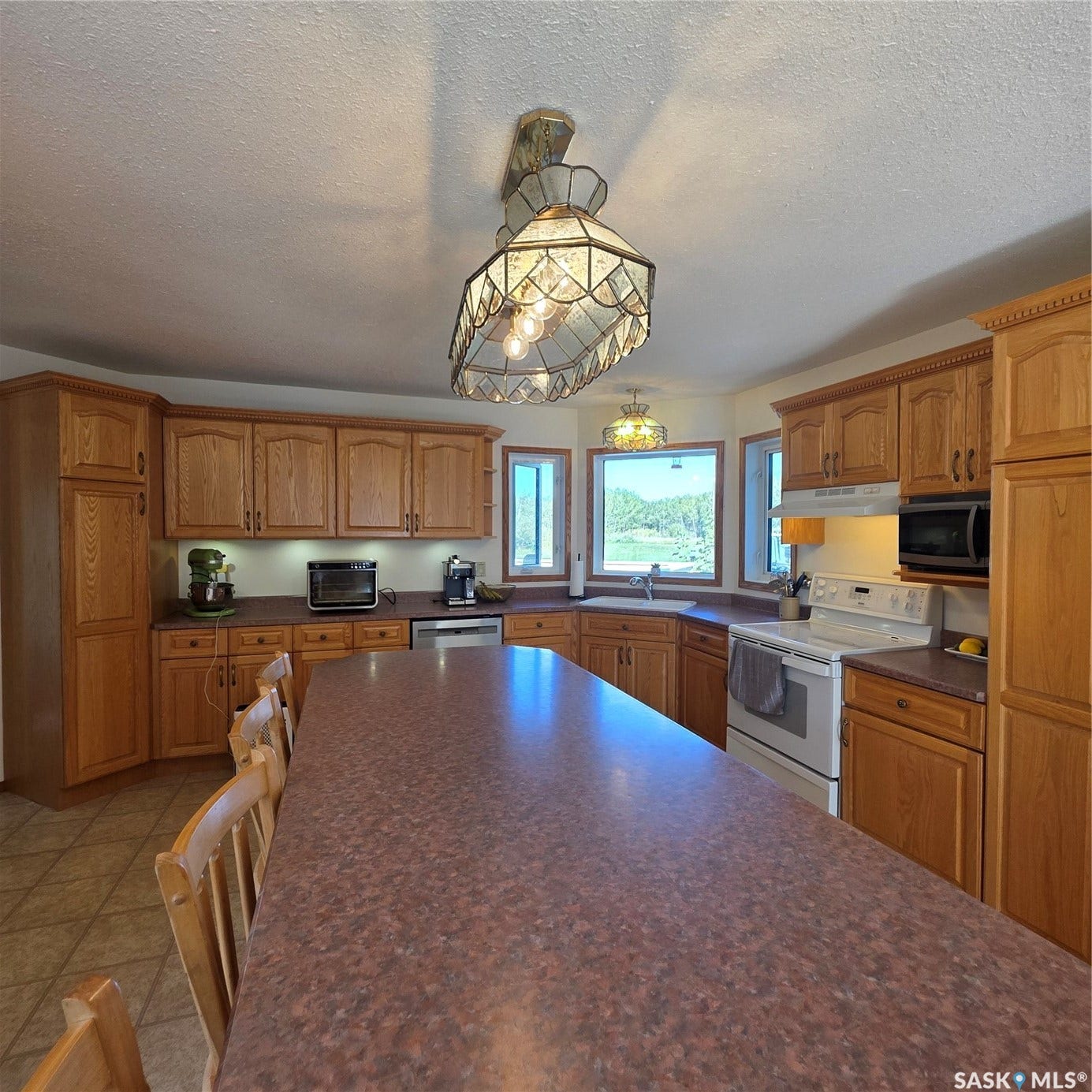 Kitchen featuring wood cabinetry, integrated appliances, and a large central island with seating