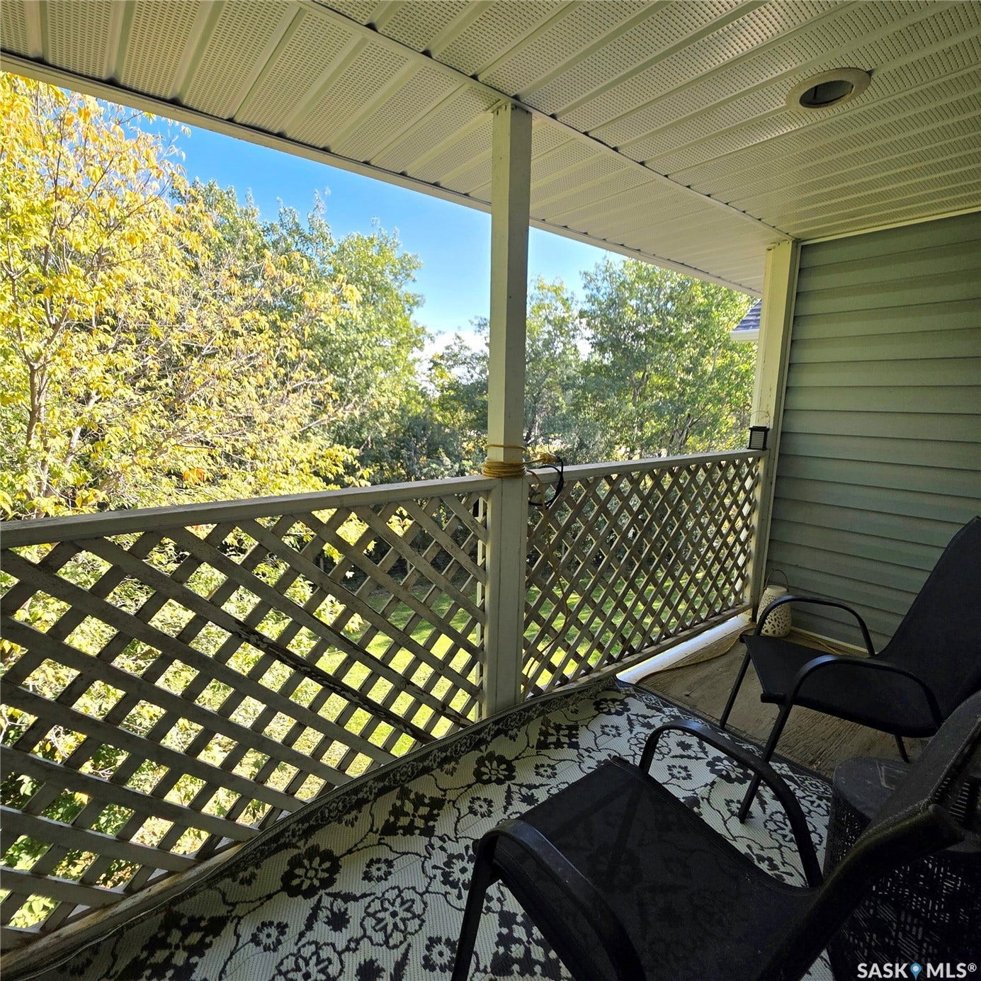 Covered outdoor balcony featuring a latticework railing, recessed lighting, and horizontal siding