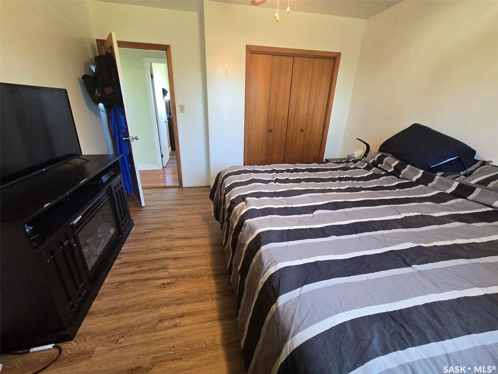 PRIMARY BEDROOM - Wood-finish flooring throughout, natural wood-finish closet doors, and light-toned wall paint
