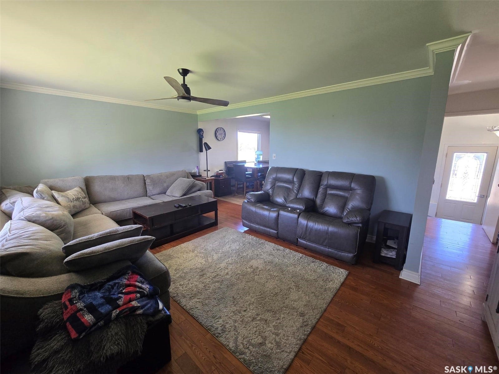 Wood-finish flooring throughout, complemented by crown molding and a ceiling fan
