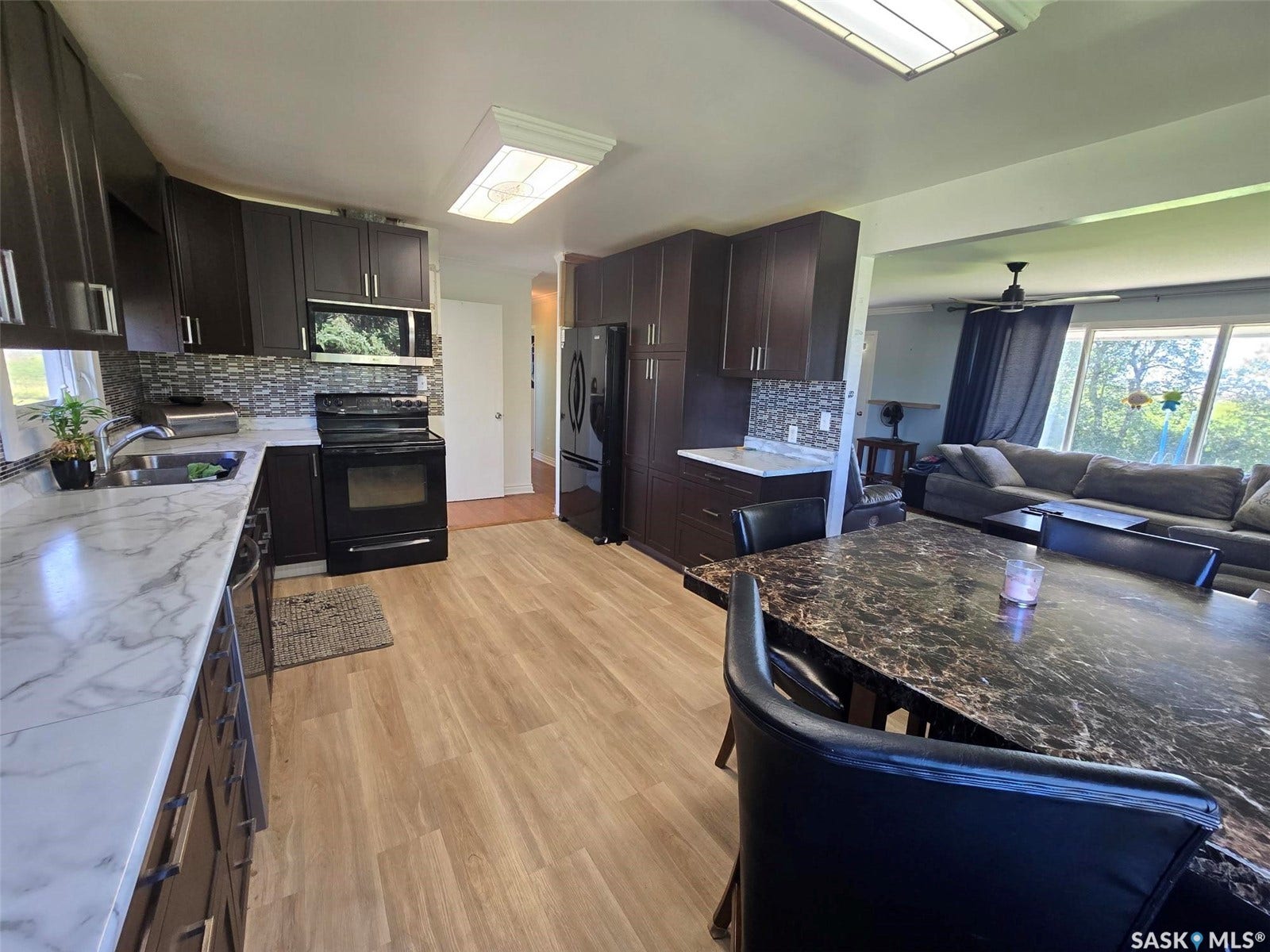 Kitchen featuring wood-finish flooring, dark wood-finish cabinetry, and light-toned countertops