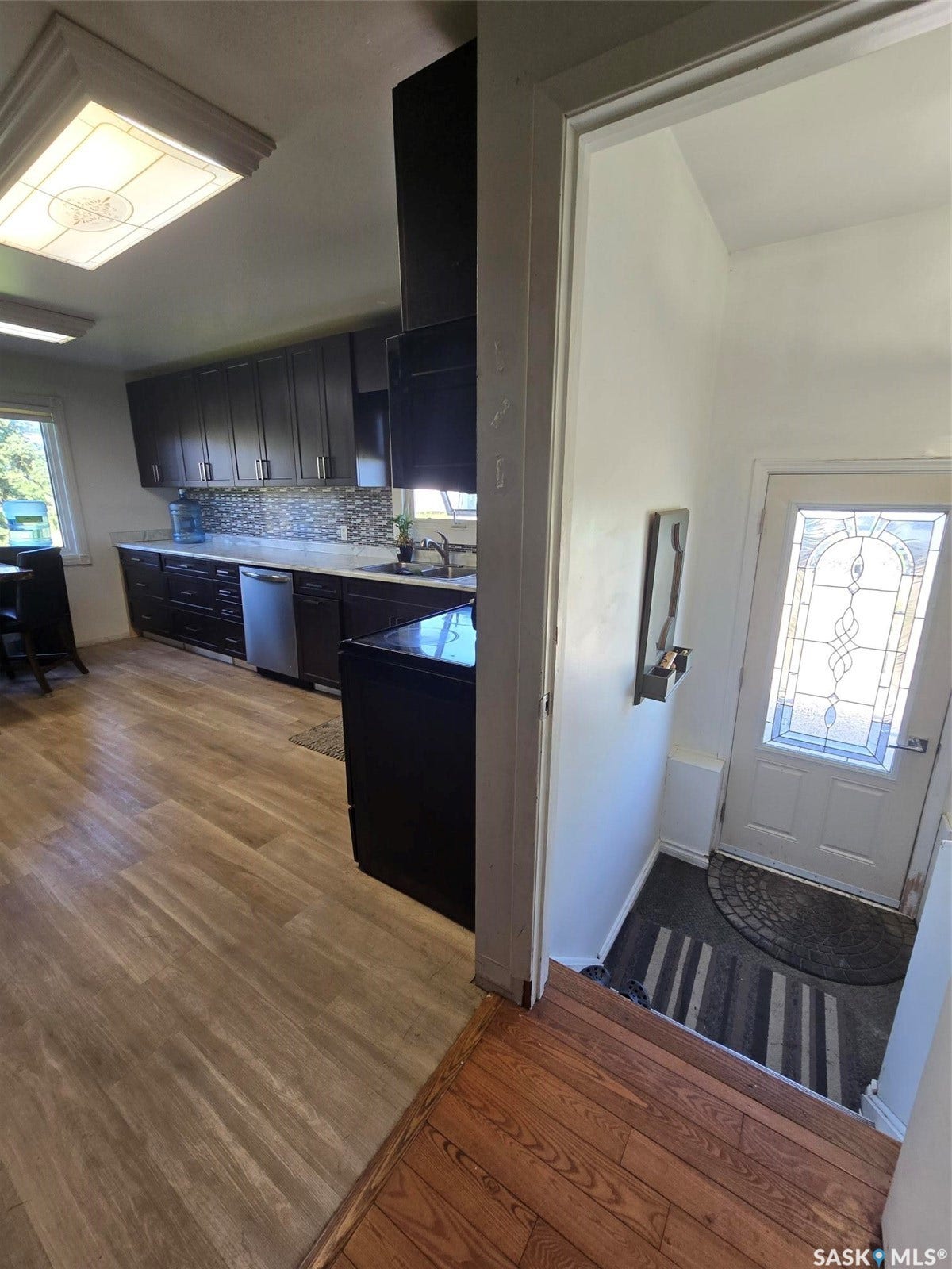 Kitchen with dark wood-finish cabinetry, light countertops, and a mosaic tile backsplash
