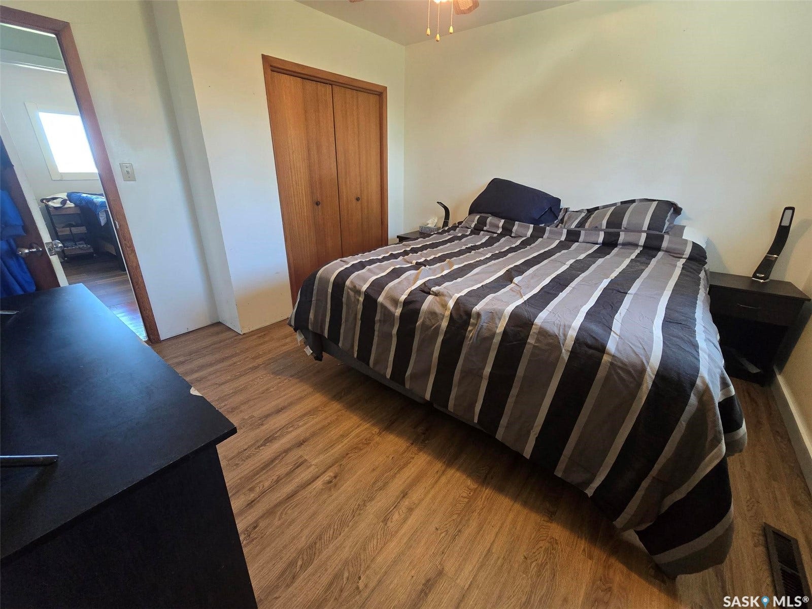 Wood-finish flooring throughout, solid wood bi-fold closet doors, and a ceiling fan with integrated lighting