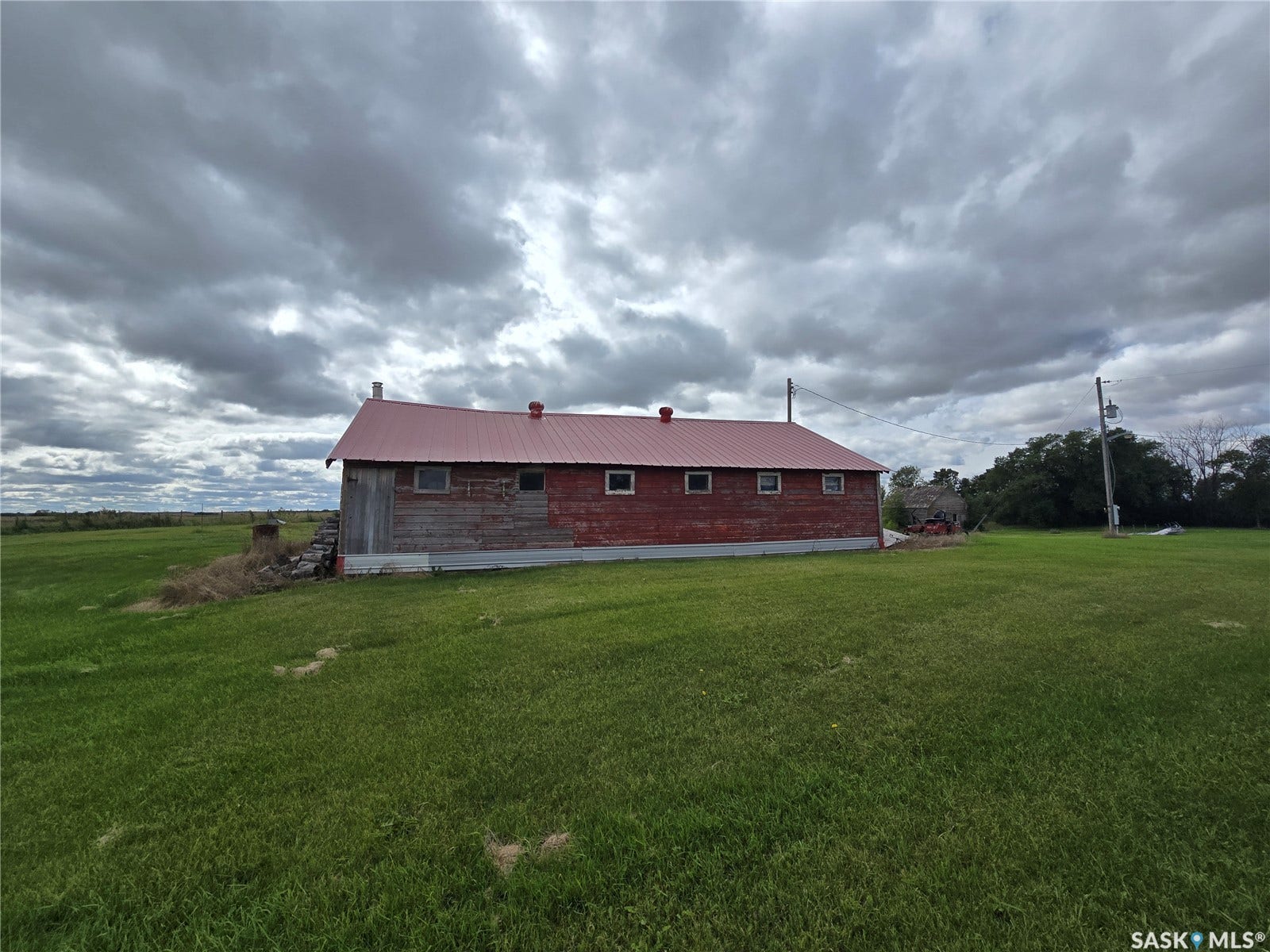 Red barn structure with a metal roof, multiple square windows, and a singular wooden door
