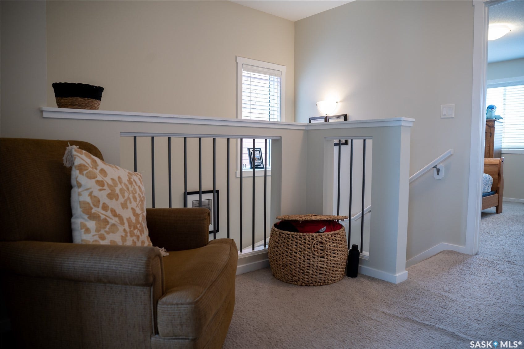 Carpeted hallway with painted walls, white trim, and a staircase featuring a white handrail and black metal balusters