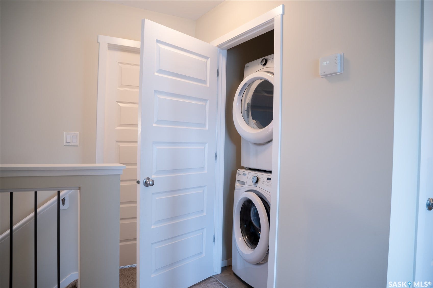Integrated laundry center with stacked appliances, white paneled doors, and contemporary wall color
