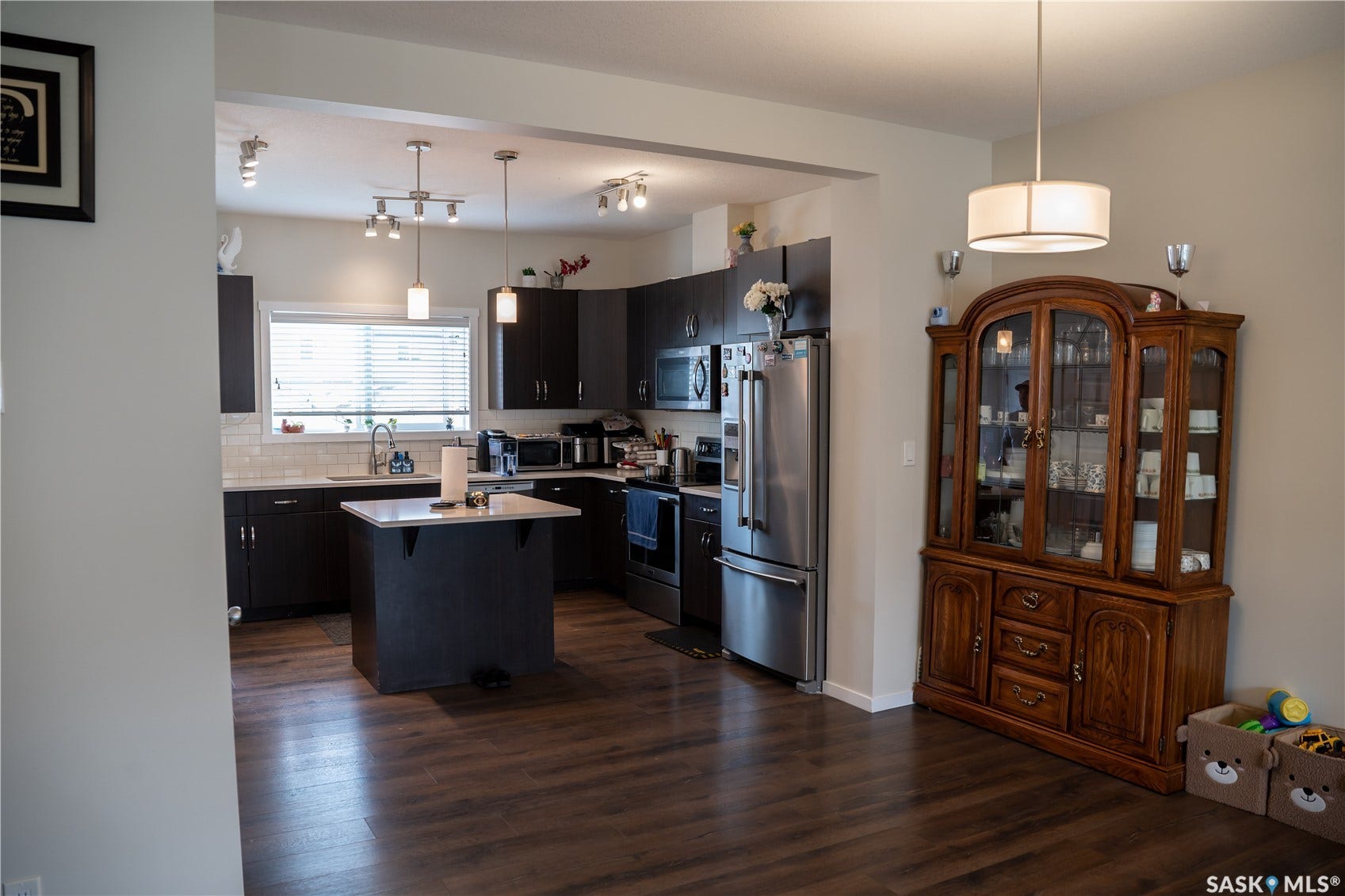Open-concept kitchen with dark wood-finish cabinetry, stainless steel appliances, and a central island
