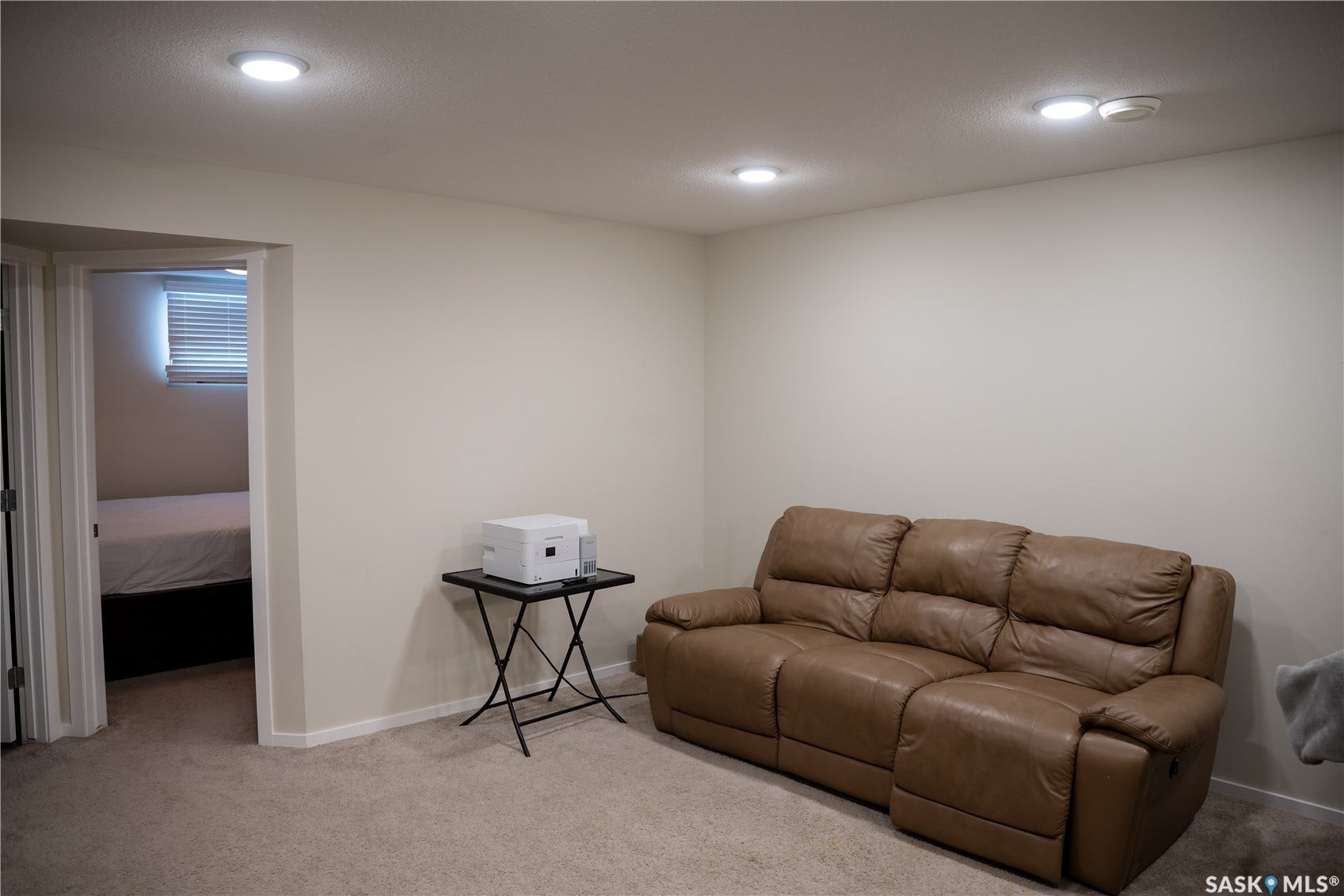 Carpeted flooring, recessed ceiling lighting, and a doorway leading to a separate room with a window