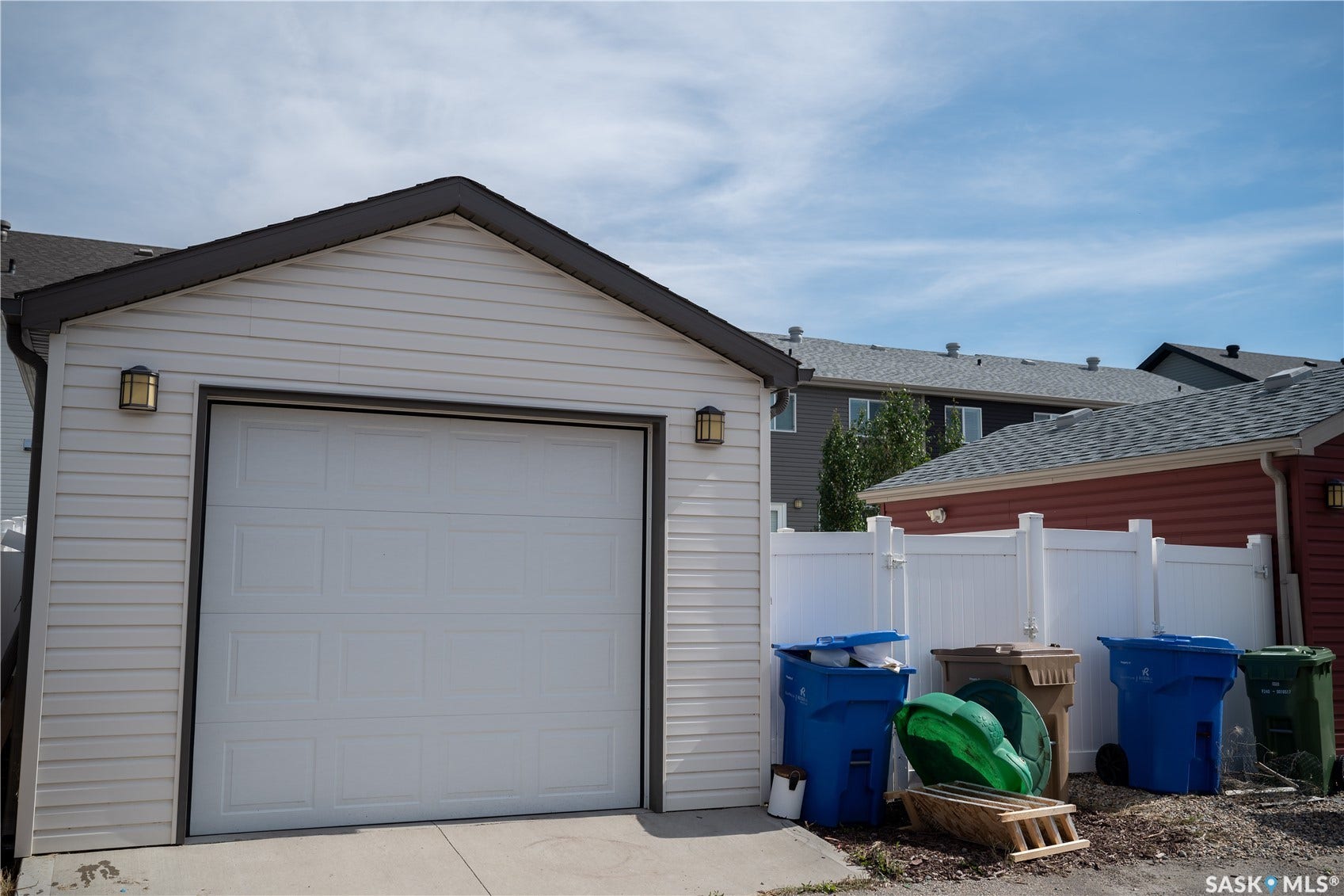 Detached garage featuring a single-car white overhead door with dark trim, horizontal vinyl siding, and a peaked roofline