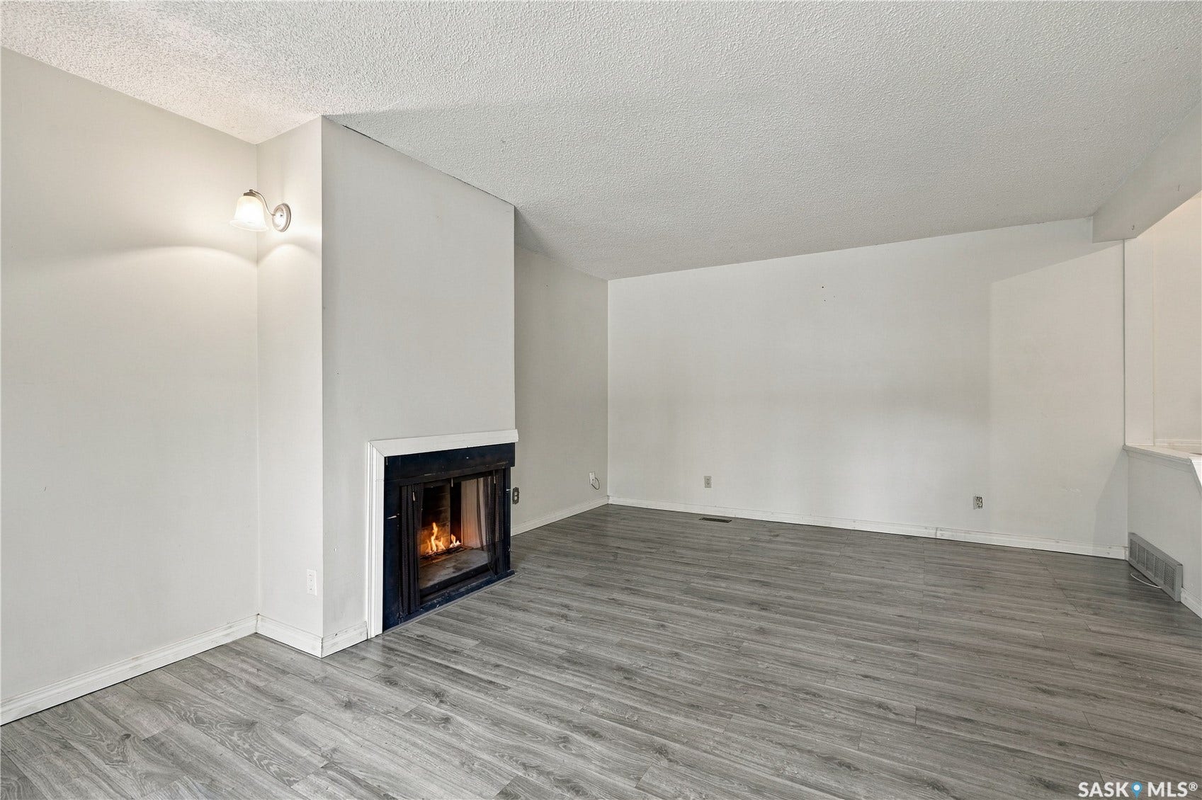 Living space featuring a built-in fireplace, wood-finish flooring, and sconce lighting