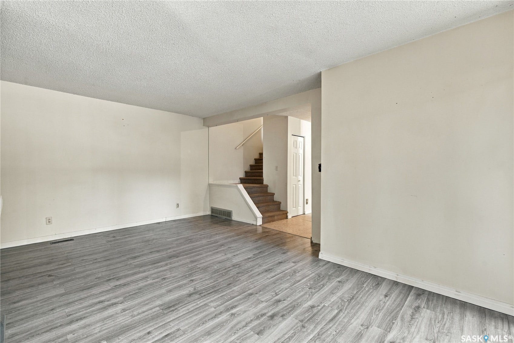 Wood-finish flooring throughout, light neutral wall paint, and staircase to 2nd level