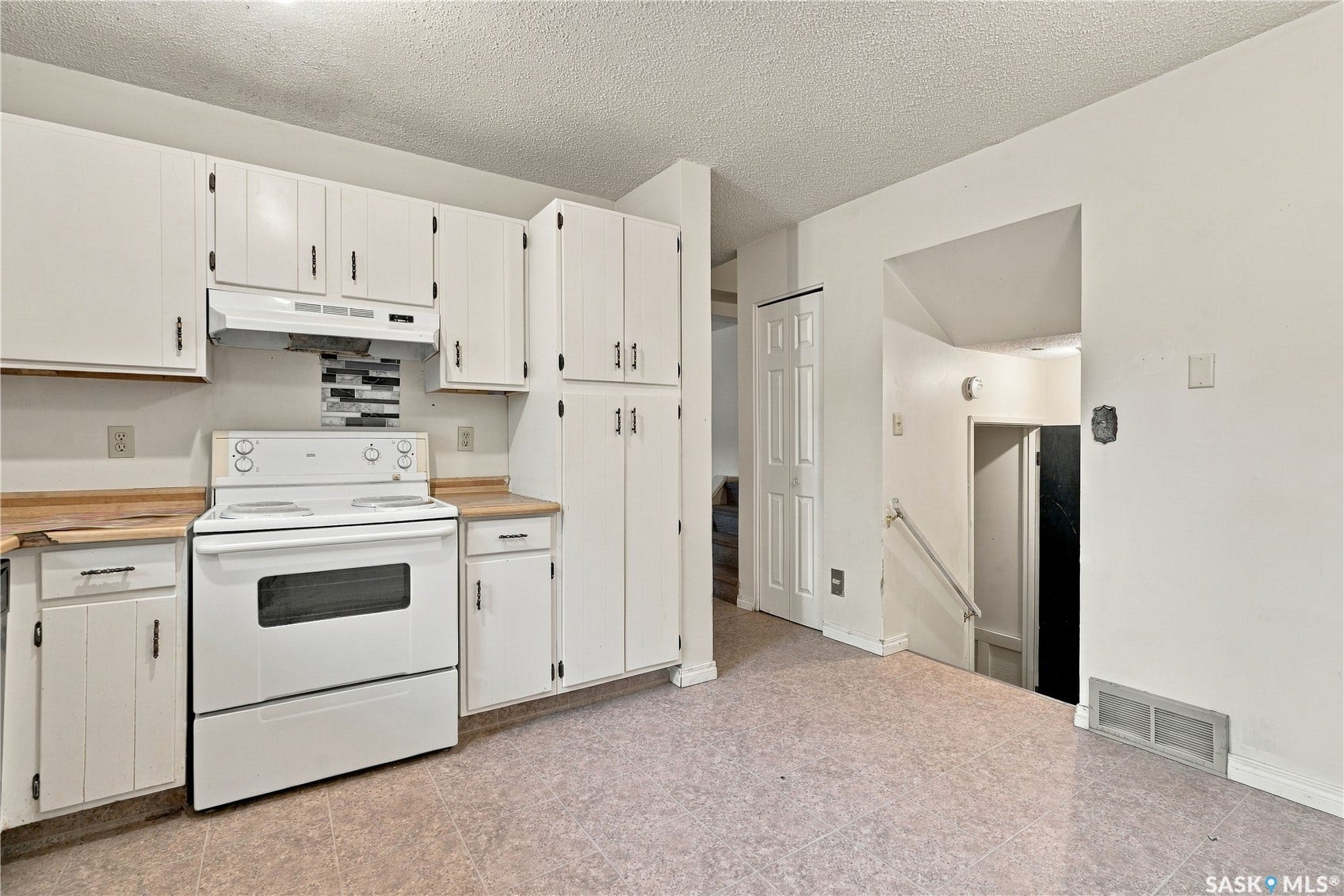 Kitchen featuring white cabinetry, a white electric range, wood-finish countertops, and a tiled backsplash