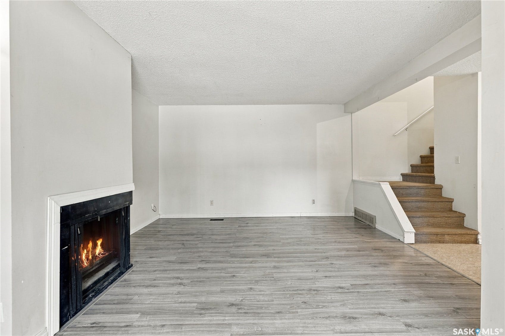 Wood-finish flooring, built-in fireplace, and staircase with carpeted treads
