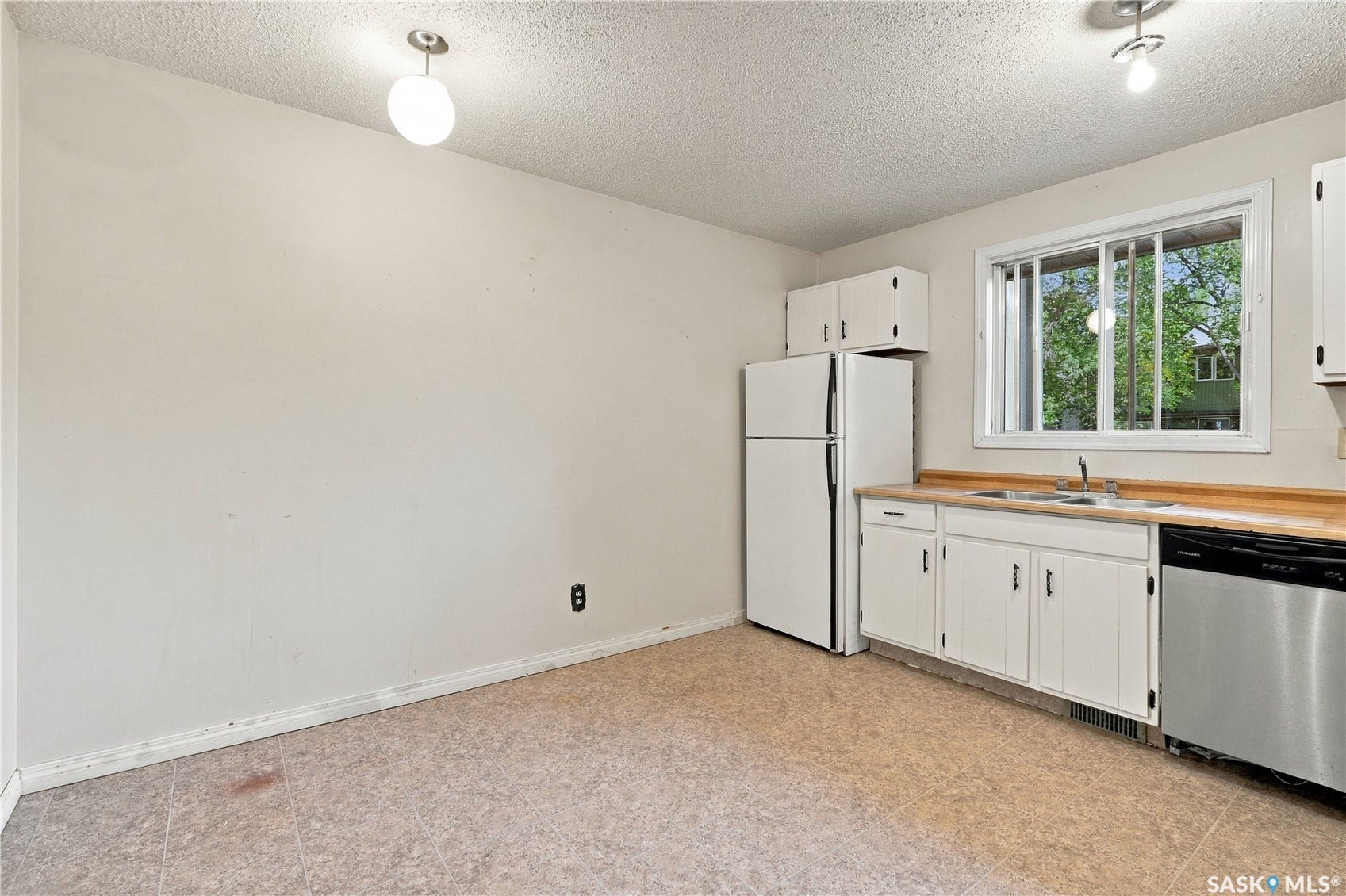 Kitchen featuring white cabinetry, a double basin sink, stainless steel dishwasher, and a window