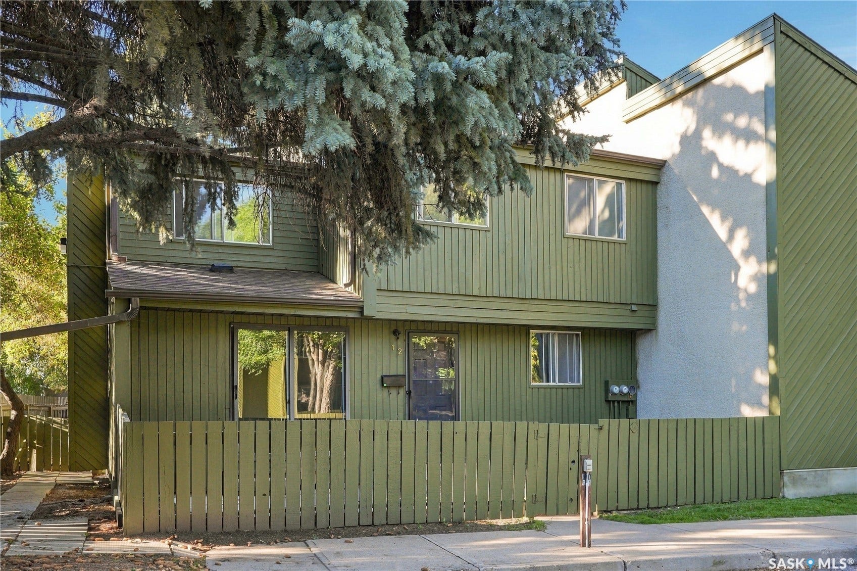 Two-story exterior with vertical siding and stucco accents, featuring a front privacy fence