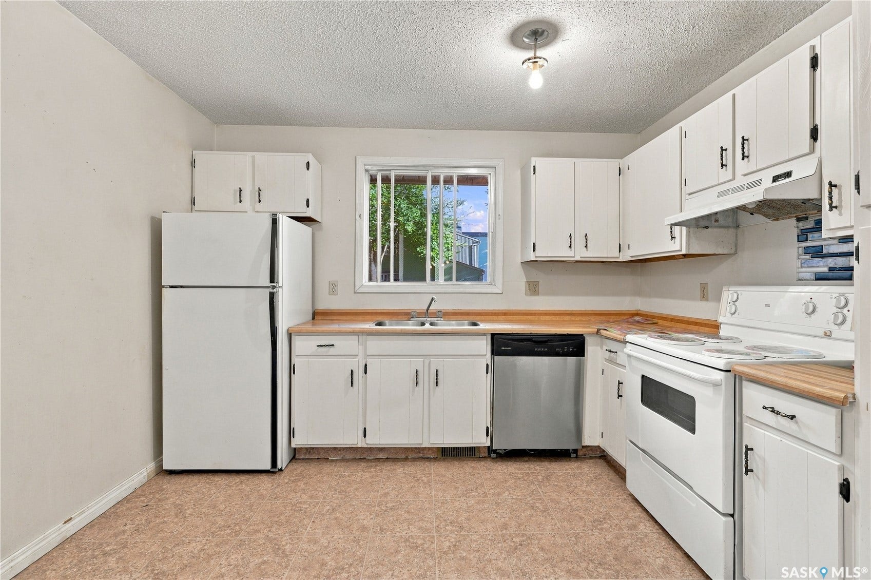 Kitchen featuring white cabinetry with dark hardware, wood-finish countertops, and a stainless steel dishwasher