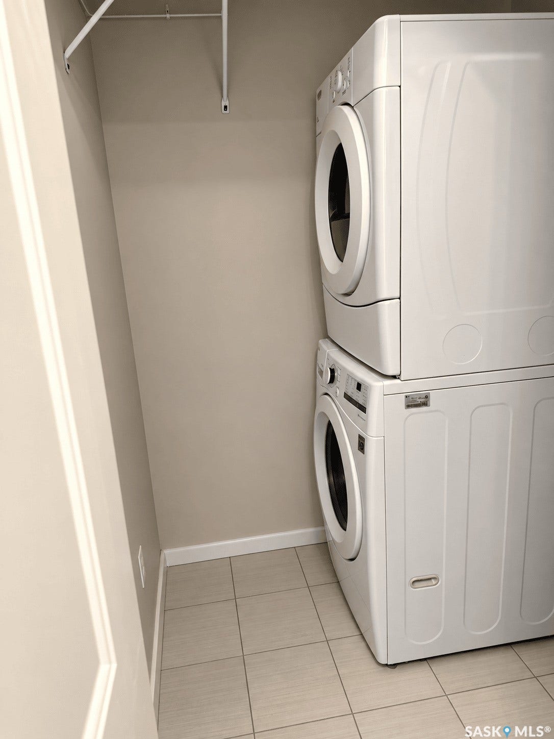 Stackable laundry appliances, wall-mounted hanging rod, and square tile flooring