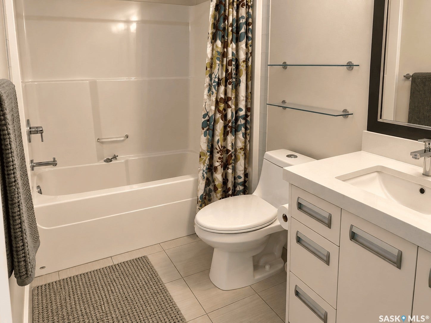 White vanity with recessed panel drawers, integrated sink, and light-toned countertop