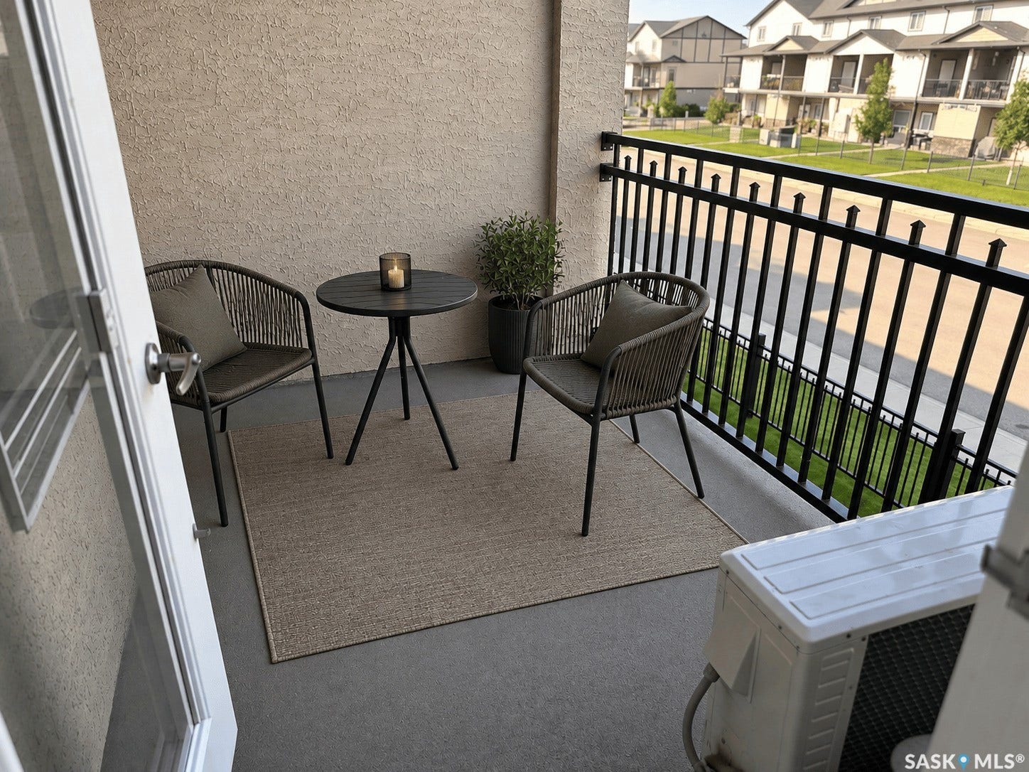 Private balcony with a black metal railing and textured exterior wall