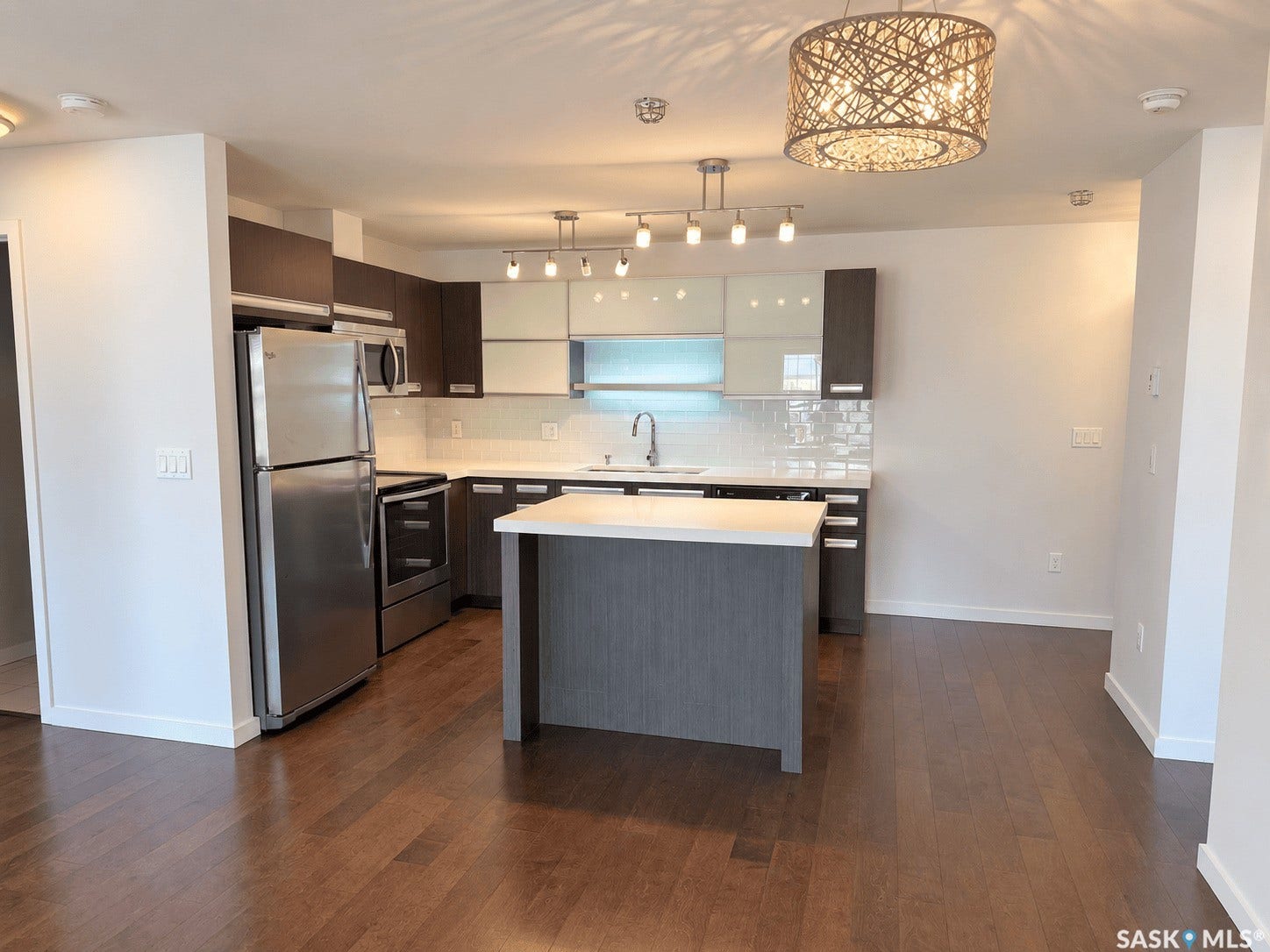 Kitchen featuring stainless steel appliances, dark wood-finish cabinetry, white countertops, and a central island