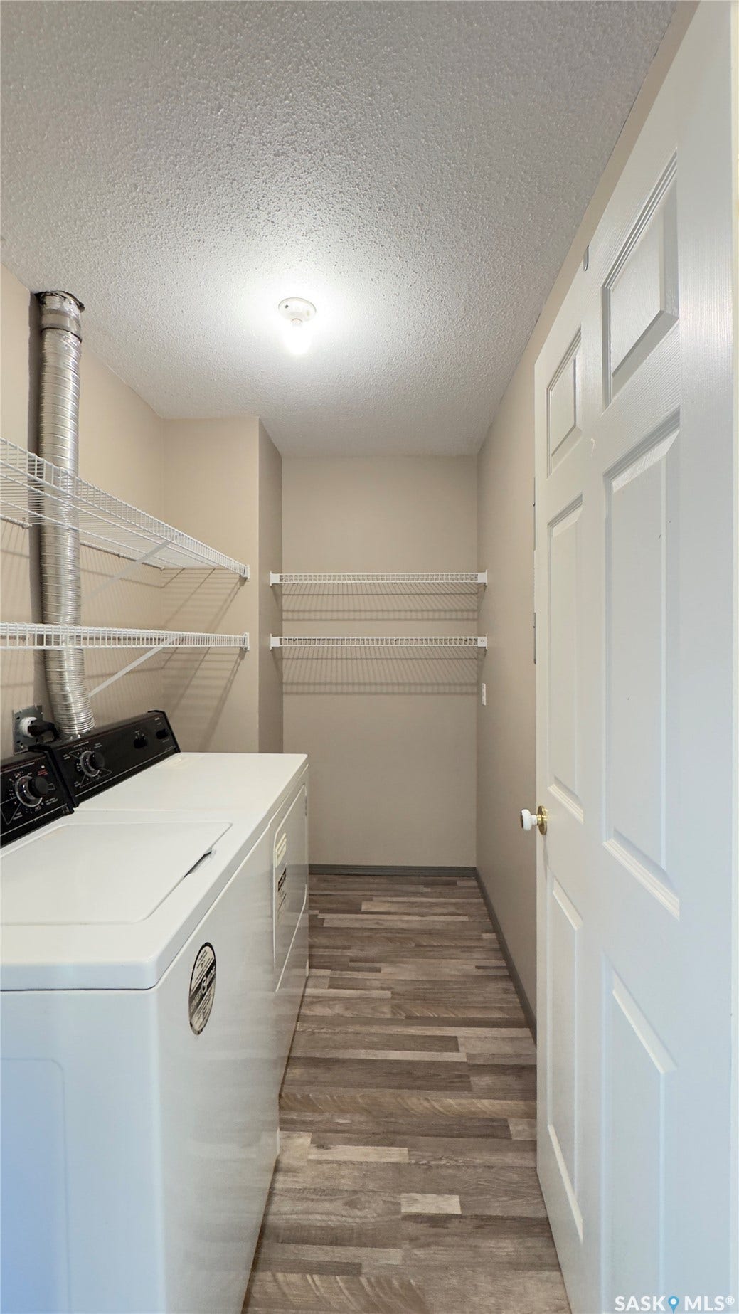 Dedicated laundry area with durable wood-finish flooring, integrated overhead lighting, and abundant wire shelving