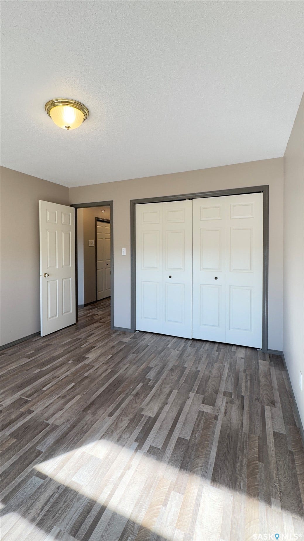 Wood-finish flooring, flush mount ceiling light, bi-fold closet doors, and painted trim throughout