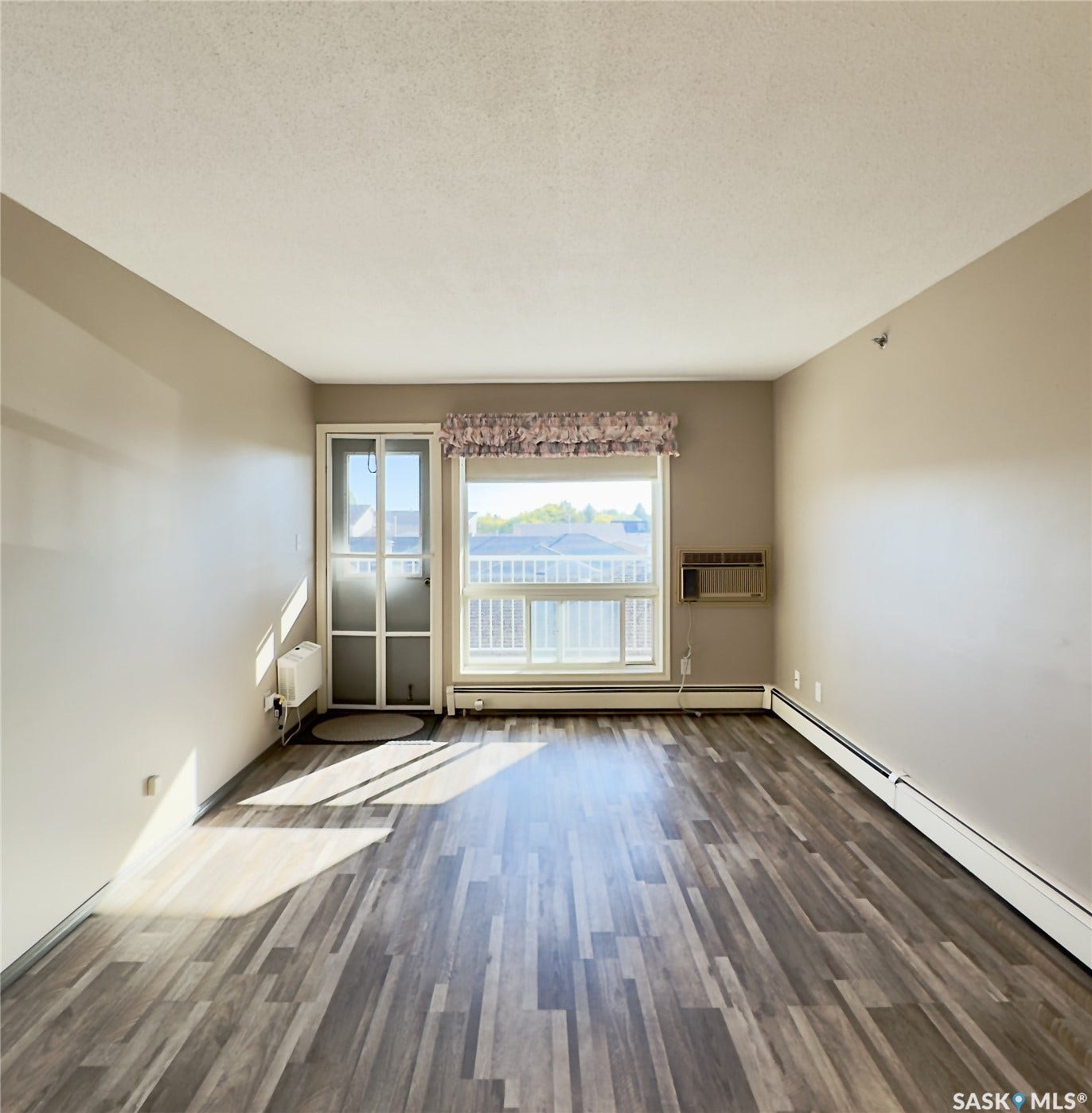Wood-finish flooring, neutral wall tones, and an integrated air conditioning unit