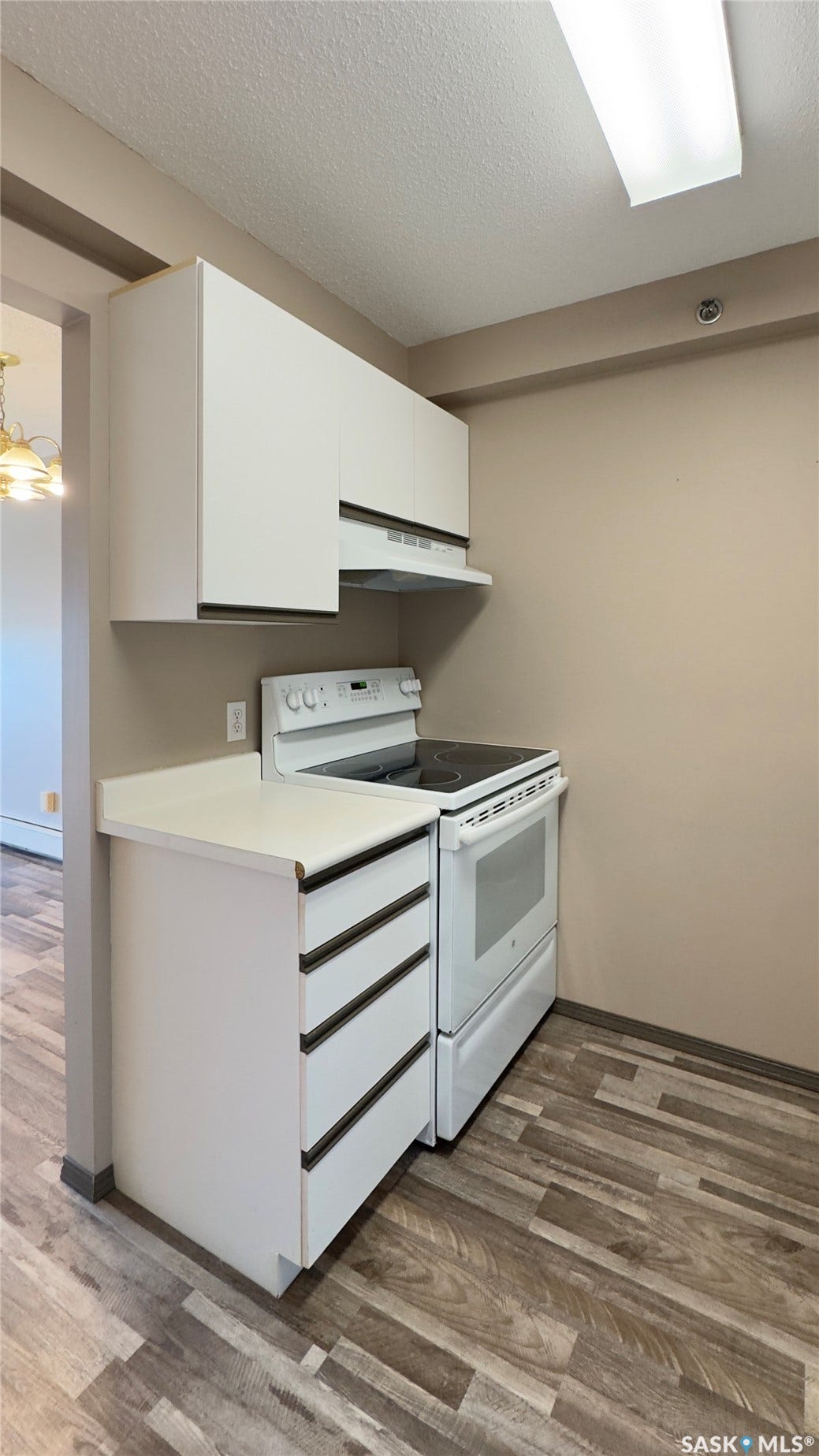 White cabinetry with integrated range hood, white electric range, white countertop, and wood-finish flooring