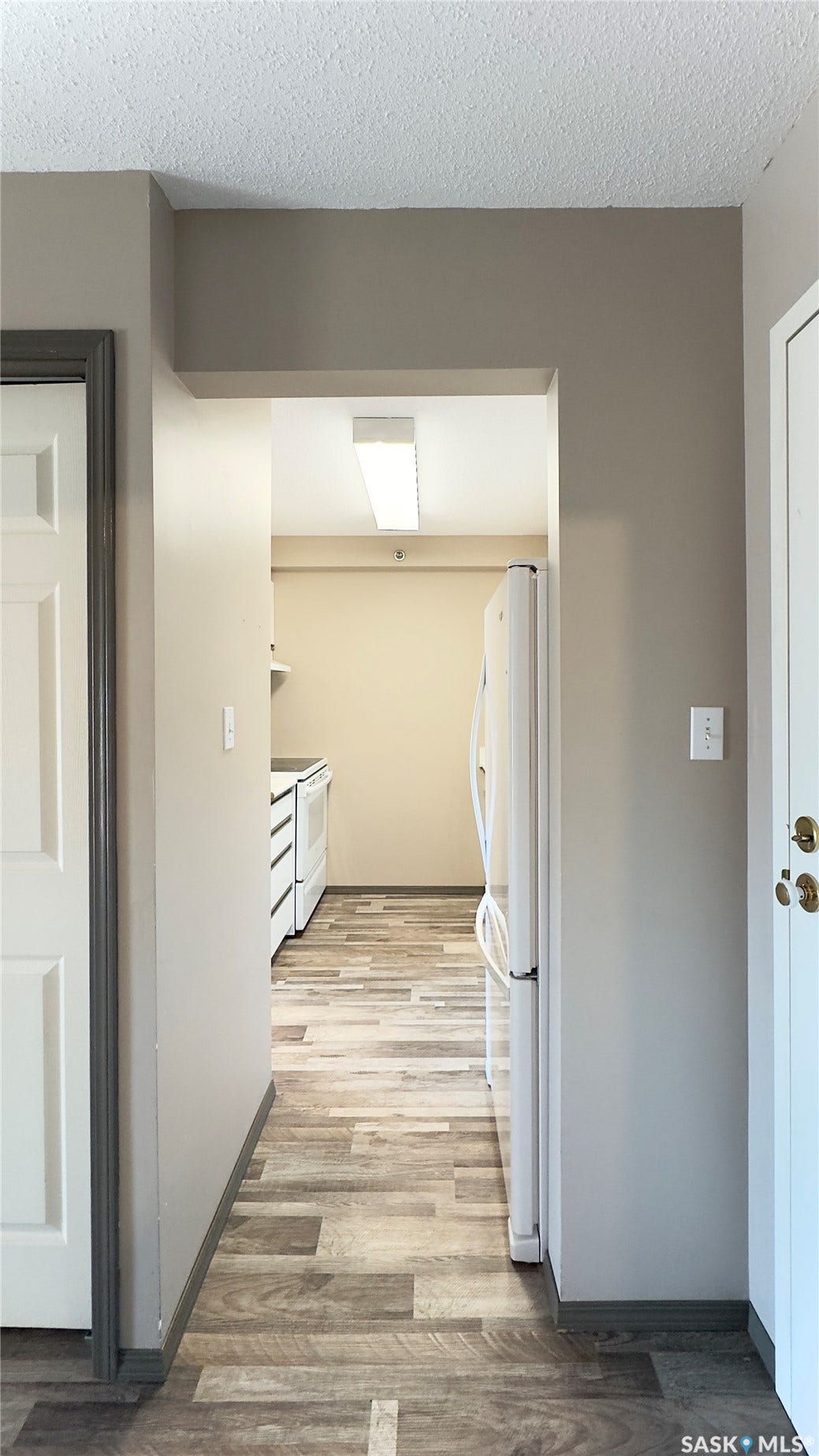 Wood-finish flooring throughout, with neutral wall paint and white appliances