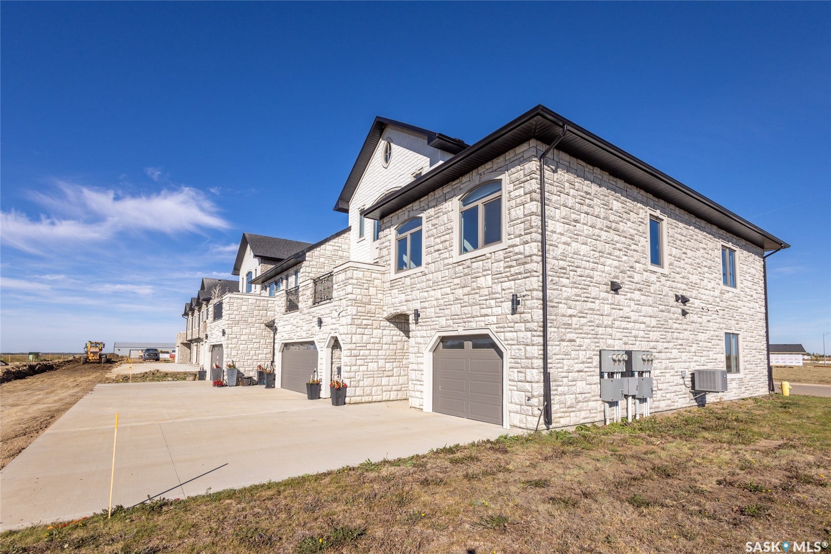 Stone veneer exterior with dark trim, arched garage doors, and individual concrete driveways