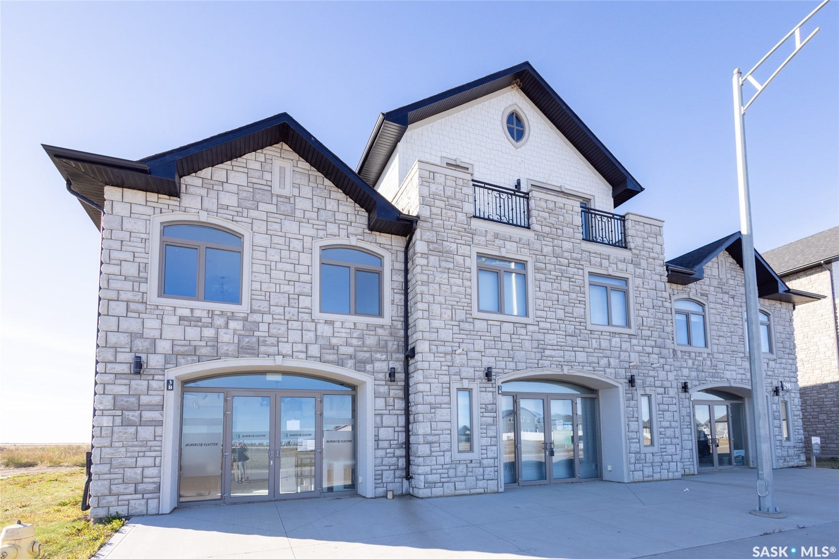 Stone facade with multiple arched windows and glass entryways